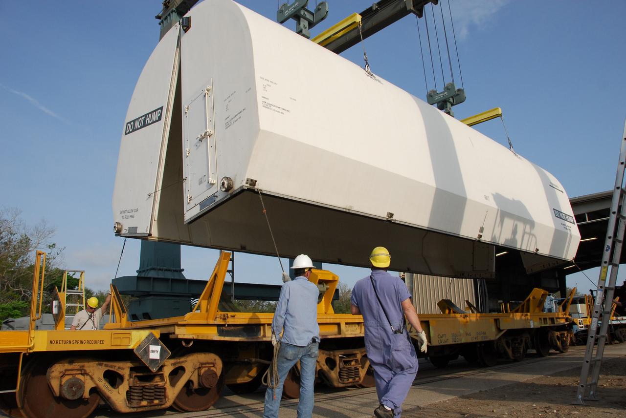 KENNEDY SPACE CENTER, FLA. --    Workers at the Railroad yard at NASA's Kennedy Space Center lift the transportation cover that will be used on solid rocket booster segments being transported to Utah.  After a mission, the spent boosters are recovered, cleaned, disassembled, refurbished and reused after each launch. After hydrolasing the interior of each segment, they are placed on flatbed trucks. The individual booster segments are transferred to a railhead located at the railroad yard.  The covered segments will be moved to Titusville for interchange with Florida East Coast Railway to begin the trip back to the Thiokol plant in Wa¬satch, Utah.   Photo credit: NASA/Jack Pfaller