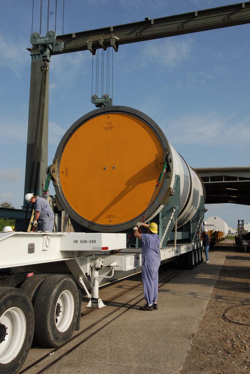 KENNEDY SPACE CENTER, FLA. --   Workers at the Railroad yard at NASA's Kennedy Space Center prepare one of the segments of a solid rocket booster from the STS-122 mission to be moved onto a railroad car for transportation to Utah.  After a mission, the spent boosters are recovered, cleaned, disassembled, refurbished and reused after each launch. After hydrolasing the interior of each segment, they are placed on flatbed trucks. The individual booster segments are transferred to a railhead located at the railroad yard.  The covered segments will be moved to Titusville for interchange with Florida East Coast Railway to begin the trip back to the Thiokol plant in Wa¬satch, Utah.   Photo credit: NASA/Jack Pfaller