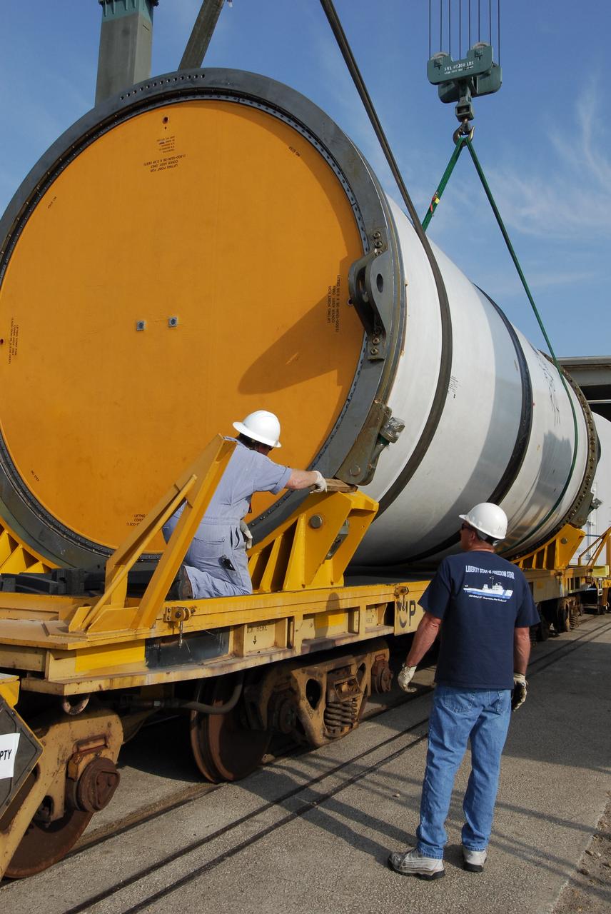 KENNEDY SPACE CENTER, FLA. --   At the Railroad yard at NASA's Kennedy Space Center, a solid rocket booster segment from the STS-122 mission is lowered onto a railroad car for transportation to Utah. After a mission, the spent boosters are recovered, cleaned, disassembled, refurbished and reused after each launch. After hydrolasing the interior of each segment, they are placed on flatbed trucks. The individual booster segments are transferred to a railhead located at the railroad yard.  The covered segments will be moved to Titusville for interchange with Florida East Coast Railway to begin the trip back to the Thiokol plant in Wa¬satch, Utah.   Photo credit: NASA/Jack Pfaller