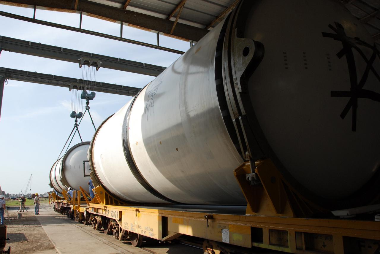 KENNEDY SPACE CENTER, FLA. --  At the Railroad yard at NASA's Kennedy Space Center, solid rocket booster segments from the STS-122 mission are being loaded onto railroad cars and covered for transportation to Utah. After a mission, the spent boosters are recovered, cleaned, disassembled, refurbished and reused after each launch. After hydrolasing the interior of each segment, they are placed on flatbed trucks. The individual booster segments are transferred to a railhead located at the railroad yard.  The covered segments will be moved to Titusville for interchange with Florida East Coast Railway to begin the trip back to the Thiokol plant in Wa¬satch, Utah.   Photo credit: NASA/Jack Pfaller