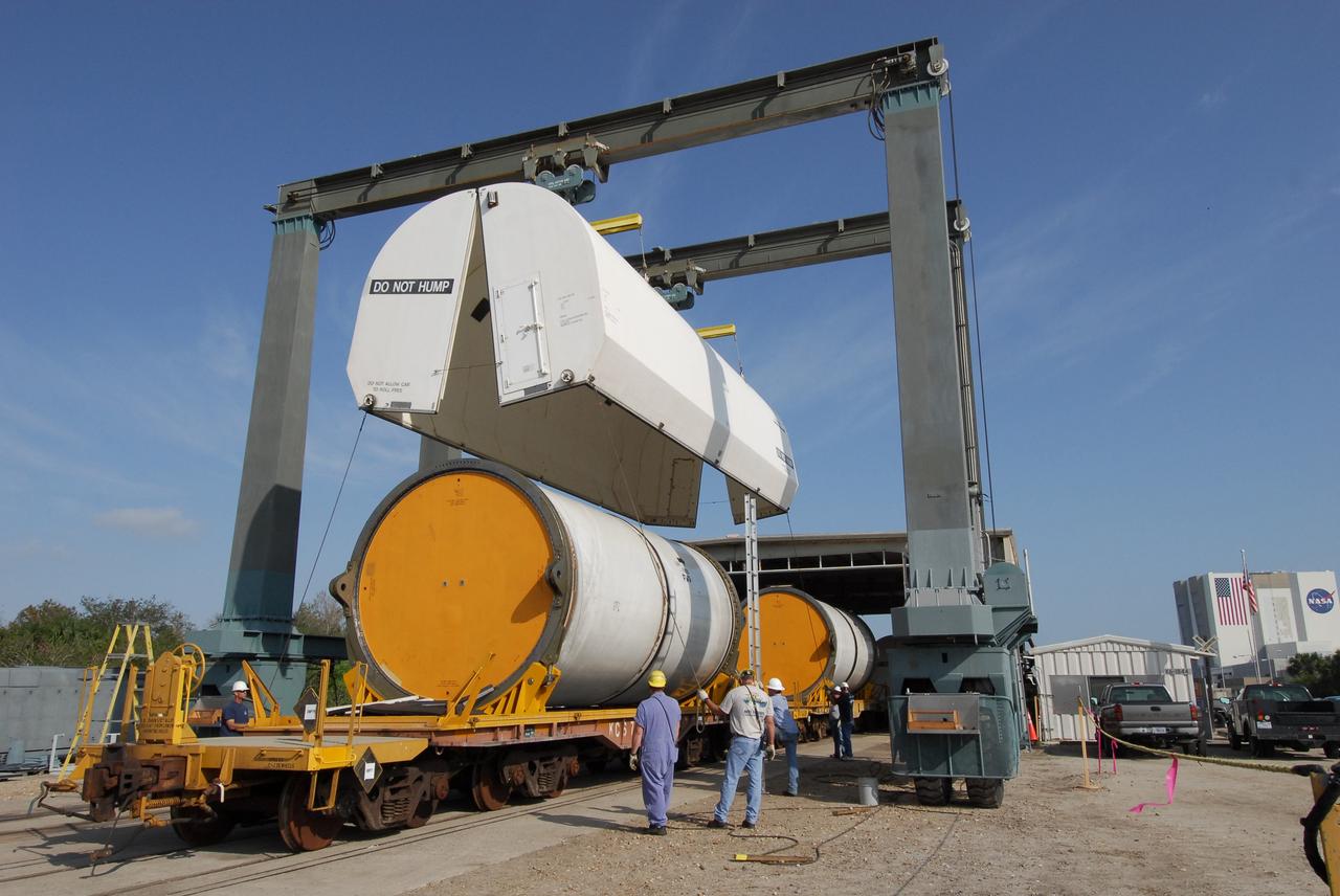 KENNEDY SPACE CENTER, FLA. --  At the NASA Railroad yard at NASA's Kennedy Space Center, workers lower a transportation cover over a solid rocket booster segment from the STS-122 mission.  Loaded on the railroad cars, the segments will be transported to Utah.  After a mission, the spent boosters are recovered, cleaned, disassembled, refurbished and reused after each launch. After hydrolasing the interior of each segment, they are placed on flatbed trucks. The individual booster segments are transferred to a railhead located at the railroad yard.  The covered segments will be moved to Titusville for interchange with Florida East Coast Railway to begin the trip back to the Thiokol plant in Wa¬satch, Utah.   Photo credit: NASA/Jack Pfaller