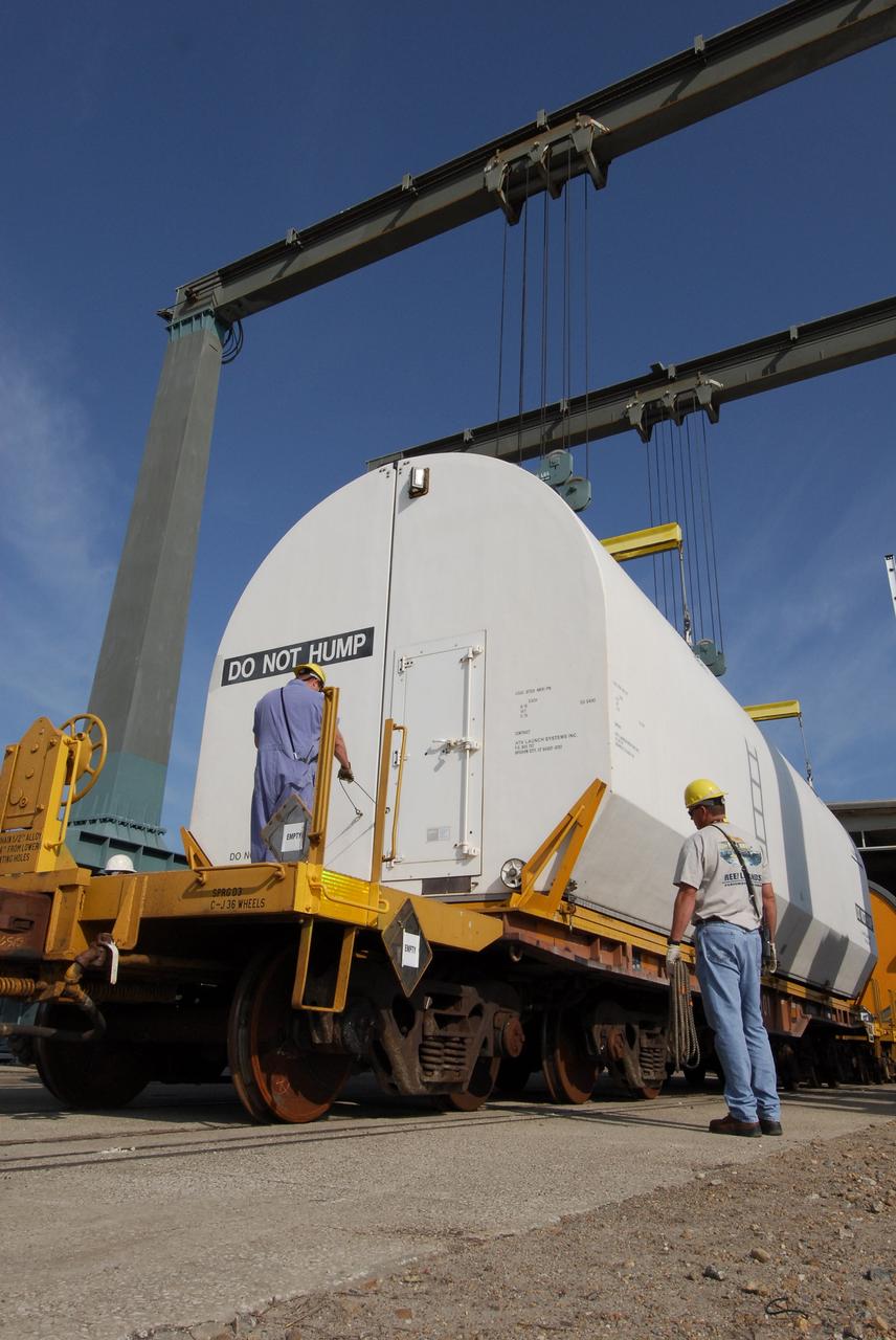 KENNEDY SPACE CENTER, FLA. --  At the NASA Railroad yard at NASA's Kennedy Space Center, a worker secures a transportation cover over a solid rocket booster segment from the STS-122 mission.  Loaded on the railroad cars, the segments will be transported to Utah.  After a mission, the spent boosters are recovered, cleaned, disassembled, refurbished and reused after each launch. After hydrolasing the interior of each segment, they are placed on flatbed trucks. The individual booster segments are transferred to a railhead located at the railroad yard.  The covered segments will be moved to Titusville for interchange with Florida East Coast Railway to begin the trip back to the Thiokol plant in Wa¬satch, Utah.   Photo credit: NASA/Jack Pfaller