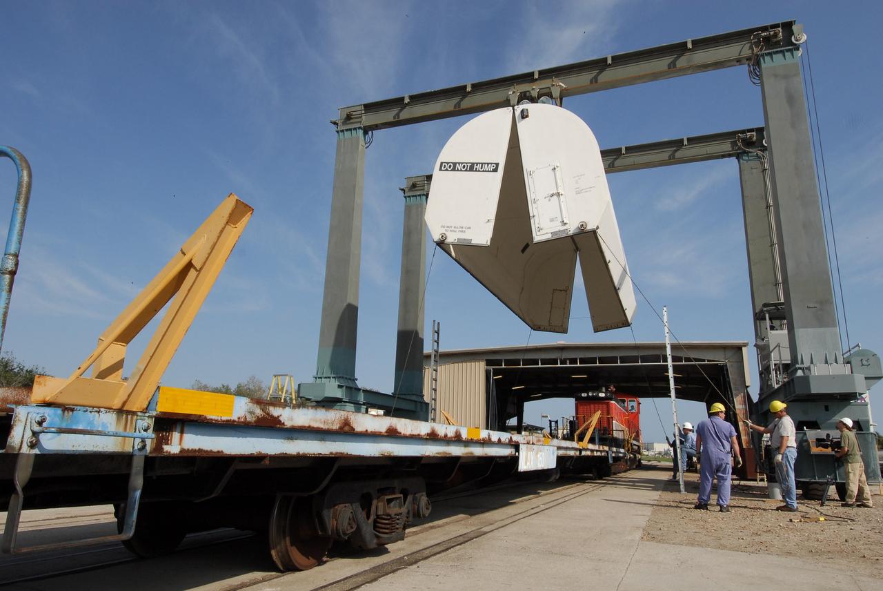 KENNEDY SPACE CENTER, FLA. --  At the NASA Railroad yard at NASA's Kennedy Space Center, a transportation cover is suspended above the railroad, waiting to be placed over another solid rocket booster segment from the STS-122 mission.  Loaded on the railroad cars, the segments will be transported to Utah.  After a mission, the spent boosters are recovered, cleaned, disassembled, refurbished and reused after each launch. After hydrolasing the interior of each segment, they are placed on flatbed trucks. The individual booster segments are transferred to a railhead located at the railroad yard.  The covered segments will be moved to Titusville for interchange with Florida East Coast Railway to begin the trip back to the Thiokol plant in Wa¬satch, Utah.   Photo credit: NASA/Jack Pfaller