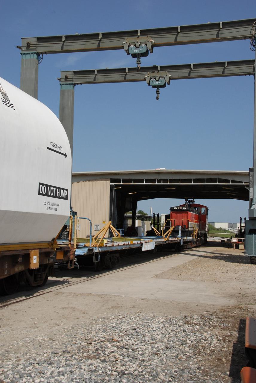 KENNEDY SPACE CENTER, FLA. --  At NASA's Kennedy Space Center, the NASA Railroad train hauling the solid rocket booster segments from the STS-122 mission begins rolling on the long journey to Utah.  After a mission, the spent boosters are recovered, cleaned, disassembled, refurbished and reused after each launch. After hydrolasing the interior of each segment, they are placed on flatbed trucks. The individual booster segments are transferred to a railhead located at the railroad yard.  The covered segments will be moved to Titusville for interchange with Florida East Coast Railway to begin the trip back to the Thiokol plant in Wa¬satch, Utah.   Photo credit: NASA/Jack Pfaller