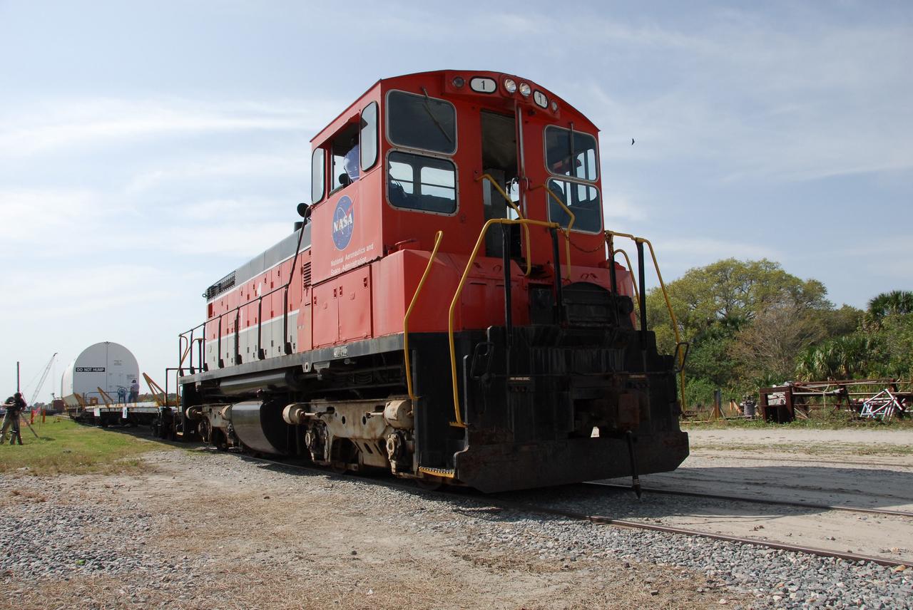 KENNEDY SPACE CENTER, FLA. --  The NASA Railroad train moves along the track away from NASA Kennedy Space Center's railroad yard.  The train is hauling the solid rocket booster segments from the STS-122 mission. After a mission, the spent boosters are recovered, cleaned, disassembled, refurbished and reused after each launch. After hydrolasing the interior of each segment, they are placed on flatbed trucks. The individual booster segments are transferred to a railhead located at the railroad yard.  The covered segments will be moved to Titusville for interchange with Florida East Coast Railway to begin the trip back to the Thiokol plant in Wa¬satch, Utah.   Photo credit: NASA/Jack Pfaller