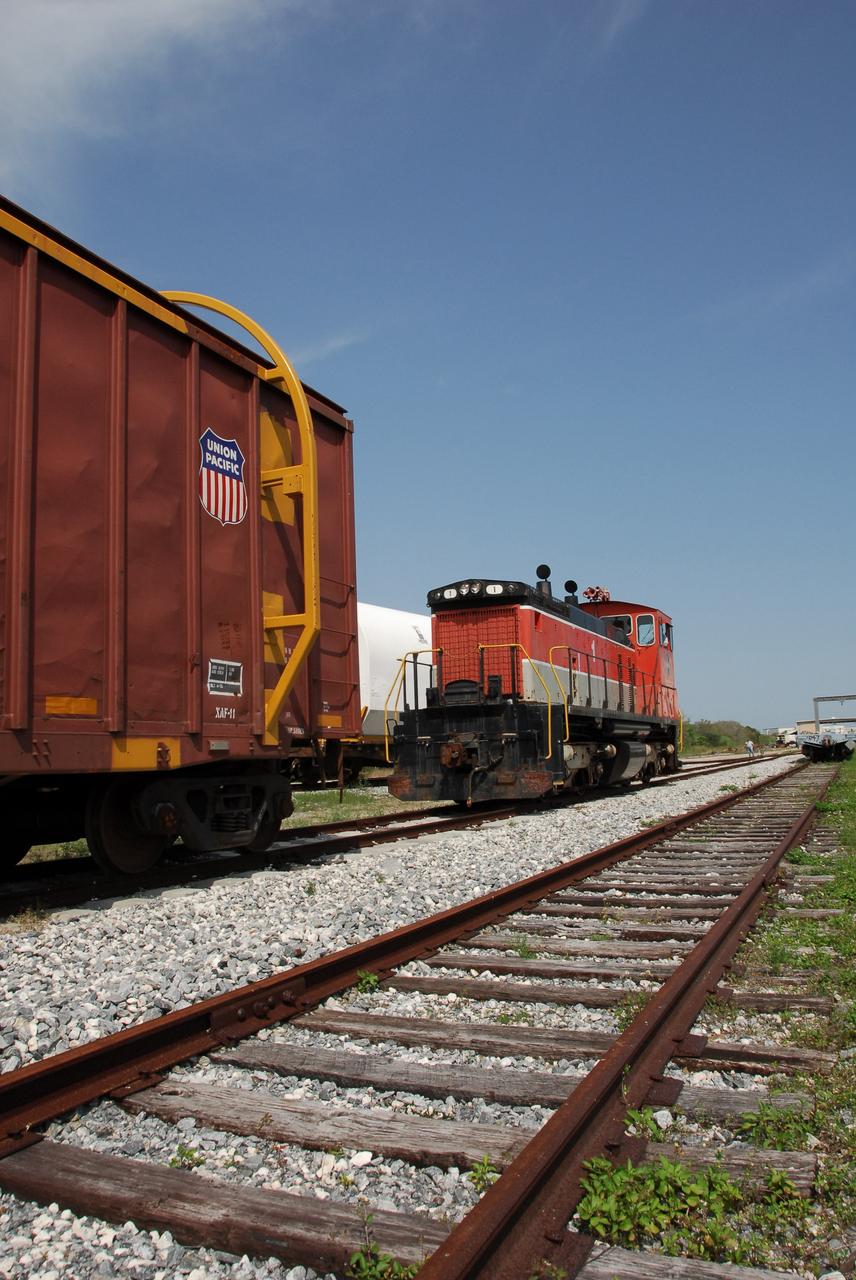 KENNEDY SPACE CENTER, FLA. --   The NASA Railroad train moves along the track in NASA Kennedy Space Center's railroad yard. The train is hauling the solid rocket booster segments from the STS-122 mission.  After a mission, the spent boosters are recovered, cleaned, disassembled, refurbished and reused after each launch. After hydrolasing the interior of each segment, they are placed on flatbed trucks. The individual booster segments are transferred to a railhead located at the railroad yard.  The covered segments will be moved to Titusville for interchange with Florida East Coast Railway to begin the trip back to the Thiokol plant in Wa¬satch, Utah.   Photo credit: NASA/Jack Pfaller