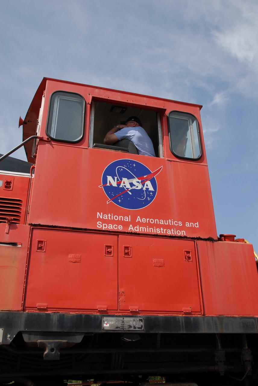 KENNEDY SPACE CENTER, FLA. --   The driver of the NASA Railroad train keeps his eye on the track ahead as the train moves through NASA Kennedy Space Center's Launch Complex 39 Area.  The train is hauling the solid rocket booster segments from the STS-122 mission.  After a mission, the spent boosters are recovered, cleaned, disassembled, refurbished and reused after each launch. After hydrolasing the interior of each segment, they are placed on flatbed trucks. The individual booster segments are transferred to a railhead located at the railroad yard.  The covered segments will be moved to Titusville for interchange with Florida East Coast Railway to begin the trip back to the Thiokol plant in Wa¬satch, Utah.   Photo credit: NASA/Jack Pfaller