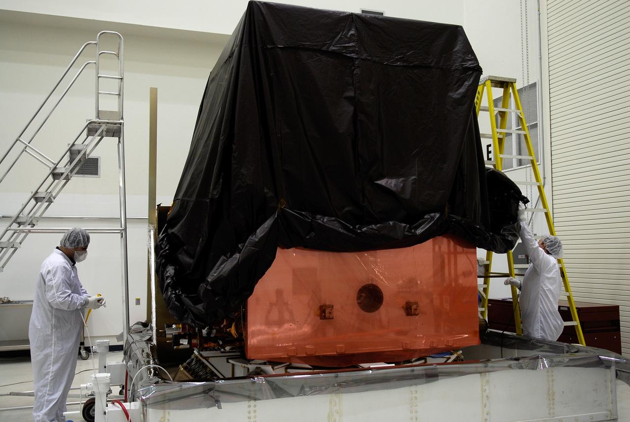 KENNEDY SPACE CENTER, FLA. -- General Dynamics technicians in the Astrotech payload processing facility begin removing the protective cover over NASA's Gamma-Ray Large Area Space Telescope, or GLAST. The space telescope will be moved to a work stand in the facility for a complete checkout of the scientific instruments aboard. The telescope will launch aboard a Delta II rocket May 16 from Launch Pad 17-B on Cape Canaveral Air Force Station. A powerful space observatory, the GLAST will explore the most extreme environments in the universe, and answer questions about supermassive black hole systems, pulsars and the origin of cosmic rays. It also will study the mystery of powerful explosions known as gamma-ray bursts. Photo credit: NASA/Kim Shiflett
