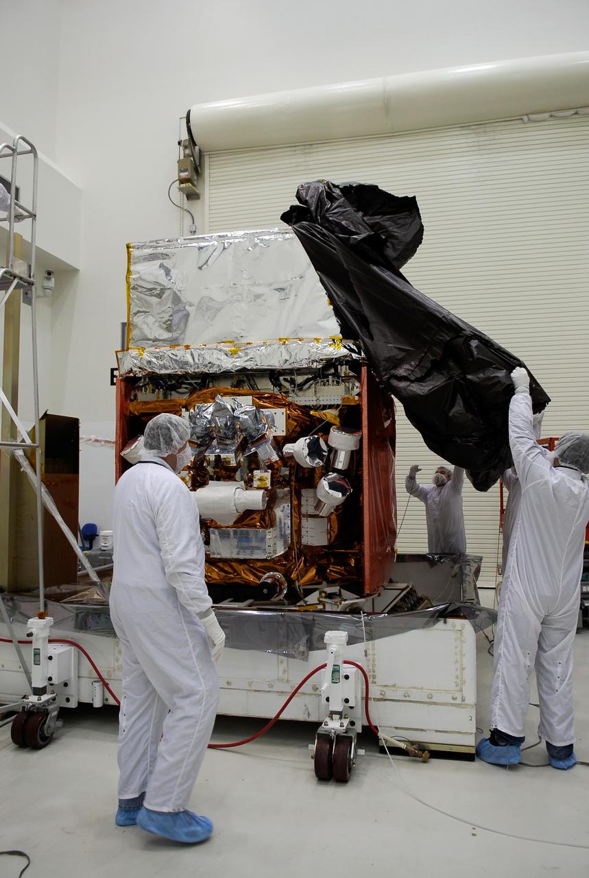 KENNEDY SPACE CENTER, FLA. -- General Dynamics technicians in the Astrotech payload processing facility remove the protective cover over NASA's Gamma-Ray Large Area Space Telescope, or GLAST. The space telescope will be moved to a work stand in the facility for a complete checkout of the scientific instruments aboard. The telescope will launch aboard a Delta II rocket May 16 from Launch Pad 17-B on Cape Canaveral Air Force Station. A powerful space observatory, the GLAST will explore the most extreme environments in the universe, and answer questions about supermassive black hole systems, pulsars and the origin of cosmic rays. It also will study the mystery of powerful explosions known as gamma-ray bursts. Photo credit: NASA/Kim Shiflett