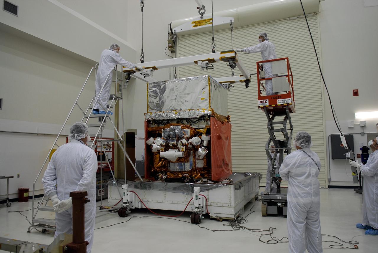 KENNEDY SPACE CENTER, FLA. -- In the Astrotech payload processing facility, General Dynamics technicians lower a crane over NASA's Gamma-Ray Large Area Space Telescope, or GLAST. After the crane is securely attached, the GLAST will be lifted and moved to a work stand in the facility for a complete checkout of the scientific instruments aboard. The telescope will launch aboard a Delta II rocket May 16 from Launch Pad 17-B on Cape Canaveral Air Force Station. A powerful space observatory, the GLAST will explore the most extreme environments in the universe, and answer questions about supermassive black hole systems, pulsars and the origin of cosmic rays. It also will study the mystery of powerful explosions known as gamma-ray bursts. Photo credit: NASA/Kim Shiflett