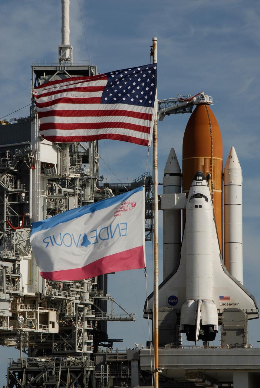 KENNEDY SPACE CENTER, FLA. -- Flags wave near Launch Pad 39A where space shuttle Endeavour waits for liftoff. The rotating service structure was rolled back starting at 8:23 a.m. and complete at 8:55 a.m. Above the orange external tank is seen the "beanie cap" at the end of the gaseous oxygen vent arm, extending from the fixed service structure. Vapors are created as the liquid oxygen in the external tank boil off. The hood vents the gaseous oxygen vapors away from the space shuttle vehicle. Below is the orbiter access arm with the White Room at the end, flush against the shuttle. The crew gains access into the orbiter through the White Room. The rotating structure provides protected access to the orbiter for changeout and servicing of payloads at the pad. The structure is supported by a rotating bridge that pivots about a vertical axis on the west side of the pad's flame trench. After the RSS is rolled back, the orbiter is ready for fuel cell activation and external tank cryogenic propellant loading operations. The pad is cleared to the perimeter gate for operations to fill the external tank with about 500,000 gallons of cryogenic propellants used by the shuttle’s main engines. This is done at the pad approximately eight hours before the scheduled launch. Endeavour and its crew will deliver the first section of the Japan Aerospace Exploration Agency's Kibo laboratory and the Canadian Space Agency's two-armed robotic system, Dextre. Launch is scheduled for 2:28 a.m. EDT March 11. Photo credit: NASA/Kim Shiflett