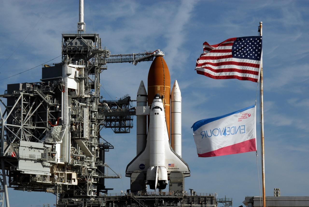 KENNEDY SPACE CENTER, FLA. -- Flags wave near Launch Pad 39A where space shuttle Endeavour waits for liftoff.  The rotating service structure was rolled back starting at 8:23 a.m. and complete at 8:55 a.m.  Above the orange external tank is seen the "beanie cap" at the end of the gaseous oxygen vent arm, extending from the fixed service structure. Vapors are created as the liquid oxygen in the external tank boil off. The hood vents the gaseous oxygen vapors away from the space shuttle vehicle.  Below is the orbiter access arm with the White Room at the end, flush against the shuttle.  The crew gains access into the orbiter through the White Room.  The rotating structure provides protected access to the orbiter for changeout and servicing of payloads at the pad. The structure is supported by a rotating bridge that pivots about a vertical axis on the west side of the pad's flame trench. After the RSS is rolled back, the orbiter is ready for fuel cell activation and external tank cryogenic propellant loading operations.  The pad is cleared to the perimeter gate for operations to fill the external tank with about 500,000 gallons of cryogenic propellants used by the shuttle’s main engines. This is done at the pad approximately eight hours before the scheduled launch.  Endeavour and its crew will deliver the first section of the Japan Aerospace Exploration Agency's Kibo laboratory and the Canadian Space Agency's two-armed robotic system, Dextre.  Launch is scheduled for 2:28 a.m. EDT March 11.  Photo credit: NASA/Kim Shiflett