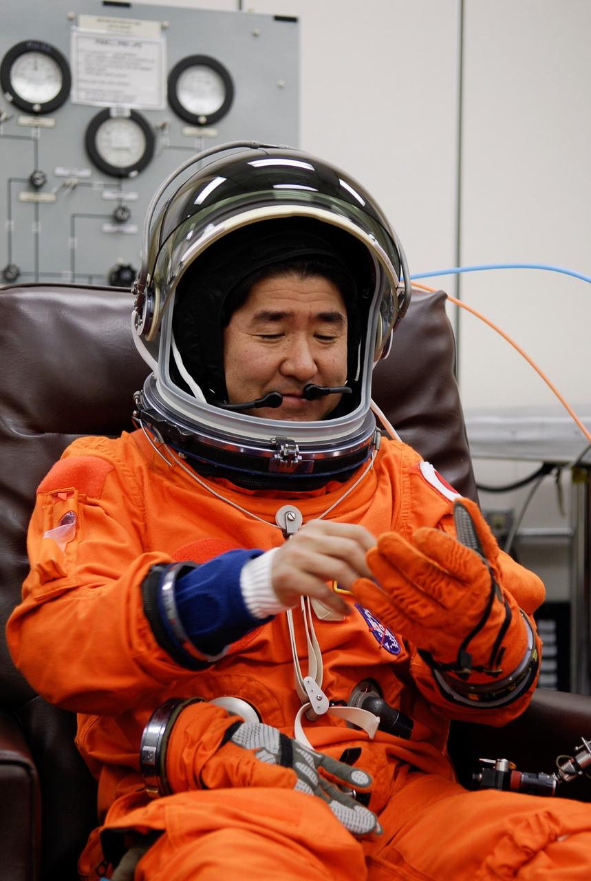 KENNEDY SPACE CENTER, FLA. -- STS-123 Mission Specialist Takao Doi of the Japan Aerospace Exploration Agency fixes his glove during suitup for launch on space shuttle Endeavour. The crew will make a record-breaking 16-day mission to the International Space Station. On STS-123, Endeavour and its crew will deliver the first section of the Japan Aerospace Exploration Agency's Kibo laboratory and the Canadian Space Agency's two-armed robotic system, Dextre. Launch is scheduled for 2:28 a.m. EDT March 11. Photo credit: NASA/Kim Shiflett