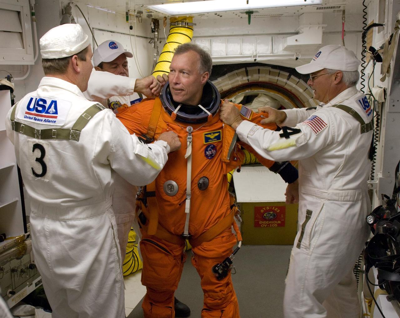 KENNEDY SPACE CENTER, FLA. -- On Launch Pad 39A at NASA's Kennedy Space Center, STS-123 Commander Dominic Gorie is helped with his final flight suit fit check in the White Room before entering space shuttle Endeavour for launch. The White Room provides access into the shuttle. Liftoff was on time at 2:28 a.m. EDT. The crew will make a record-breaking 16-day mission to the International Space Station and deliver the first section of the Japan Aerospace Exploration Agency's Kibo laboratory and the Canadian Space Agency's two-armed robotic system, Dextre. Photo credit: NASA/Scott Haun, Richard Prickett