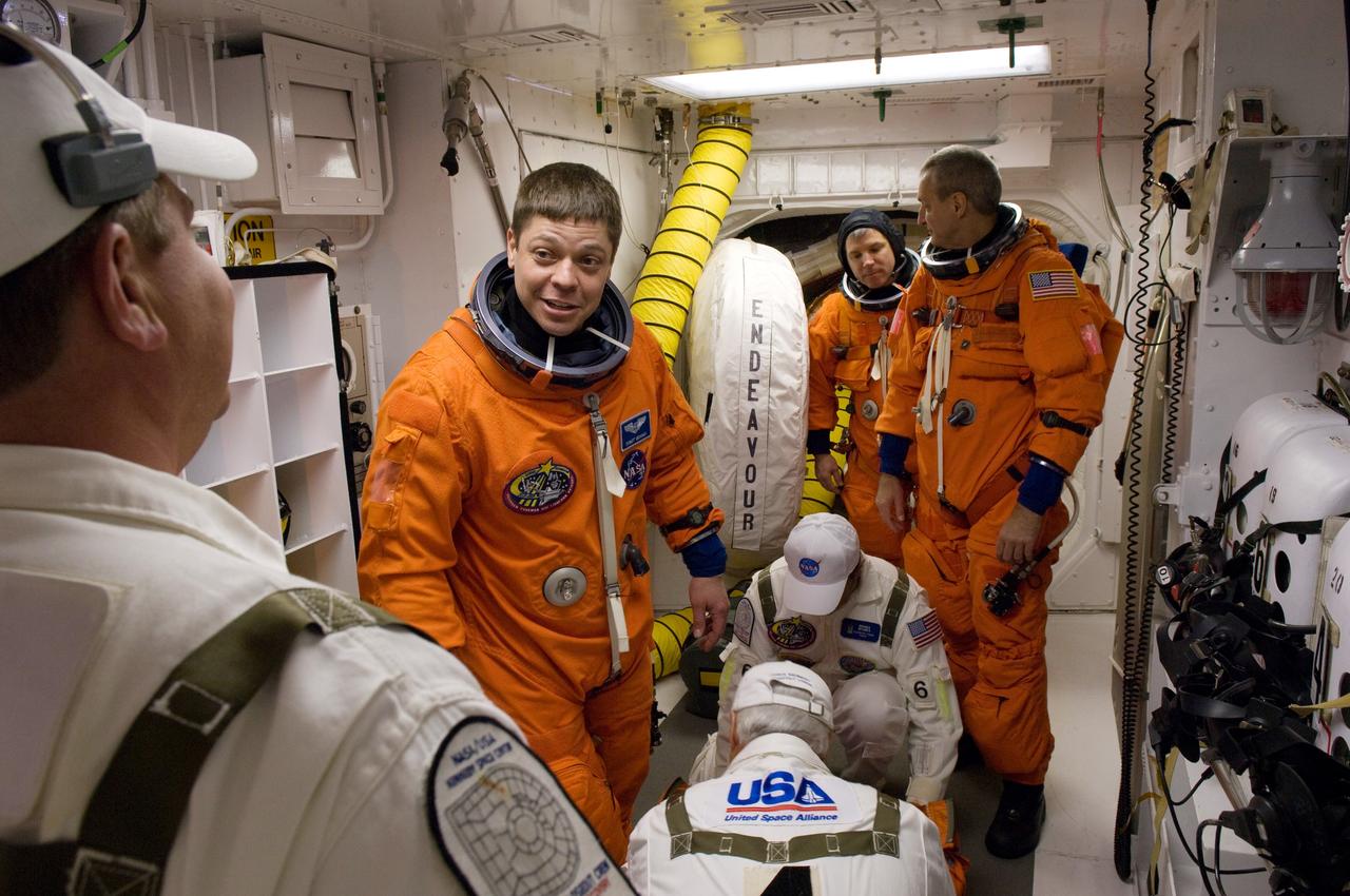 KENNEDY SPACE CENTER, FLA. -- On Launch Pad 39A at NASA's Kennedy Space Center, STS-123 crew members are getting help with their final flight suit fit check in the White Room before entering space shuttle Endeavour for launch. In the foreground is Mission Specialist Robert L. Behnken; in the background are Pilot Gregory H. Johnson (left) and Mission Specialist Rick Linnehan. The White Room provides access into the shuttle. Liftoff was on time at 2:28 a.m. EDT. The crew will make a record-breaking 16-day mission to the International Space Station and deliver the first section of the Japan Aerospace Exploration Agency's Kibo laboratory and the Canadian Space Agency's two-armed robotic system, Dextre. Photo credit: NASA/Scott Haun, Richard Prickett
