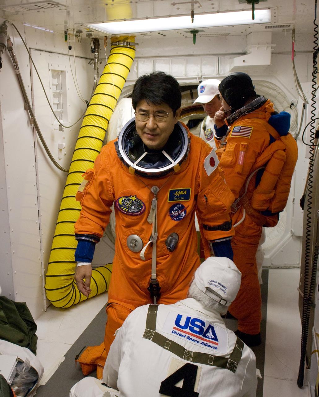 KENNEDY SPACE CENTER, FLA. -- On Launch Pad 39A at NASA's Kennedy Space Center, STS-123 Mission Specialist Takao Doi of the Japan Aerospace Exploration Agency is helped with the final flight suit fit check in the White Room before entering space shuttle Endeavour for launch. In the background is Mission Specialist Robert L. Behnken. The White Room provides access into the shuttle. Liftoff was on time at 2:28 a.m. EDT. The crew will make a record-breaking 16-day mission to the International Space Station and deliver the first section of the Japan Aerospace Exploration Agency's Kibo laboratory and the Canadian Space Agency's two-armed robotic system, Dextre. Photo credit: NASA/Scott Haun, Richard Prickett