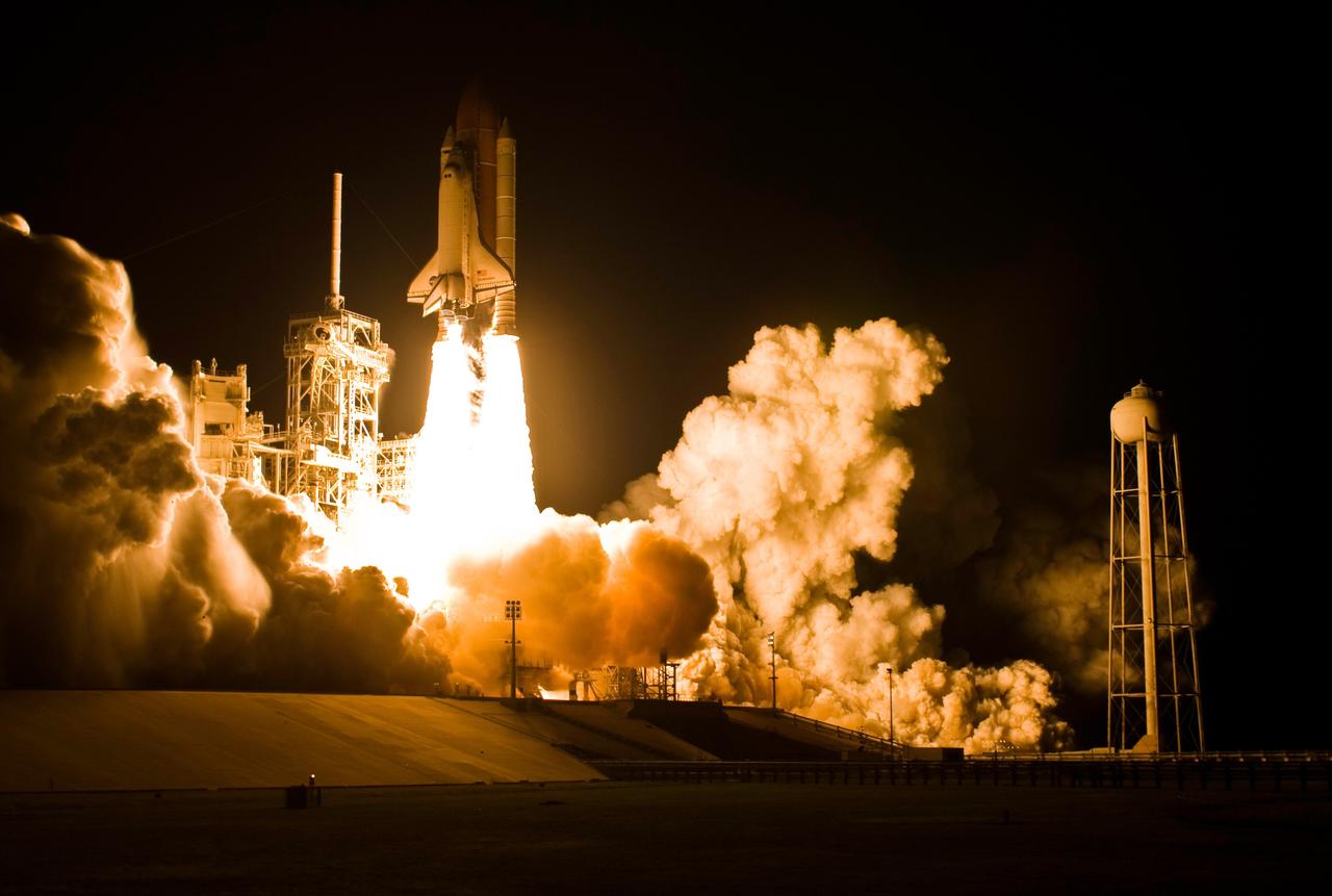KENNEDY SPACE CENTER, FLA. -- Light-filled clouds of smoke and steam roll across Launch Pad 39A at NASA's Kennedy Space Center as space shuttle Endeavour roars into the night sky atop twin towers of flame on the STS-123 mission. At right is the 300,000-gallon water tower that provides the water used for sound suppression on the pad at liftoff. The liftoff was on time at 2:28 a.m. EDT. Endeavour's crew will make a record-breaking 16-day mission to the International Space Station and deliver the first section of the Japan Aerospace Exploration Agency's Kibo laboratory and the Canadian Space Agency's two-armed robotic system, Dextre. Photo courtesy of Scott Andrews