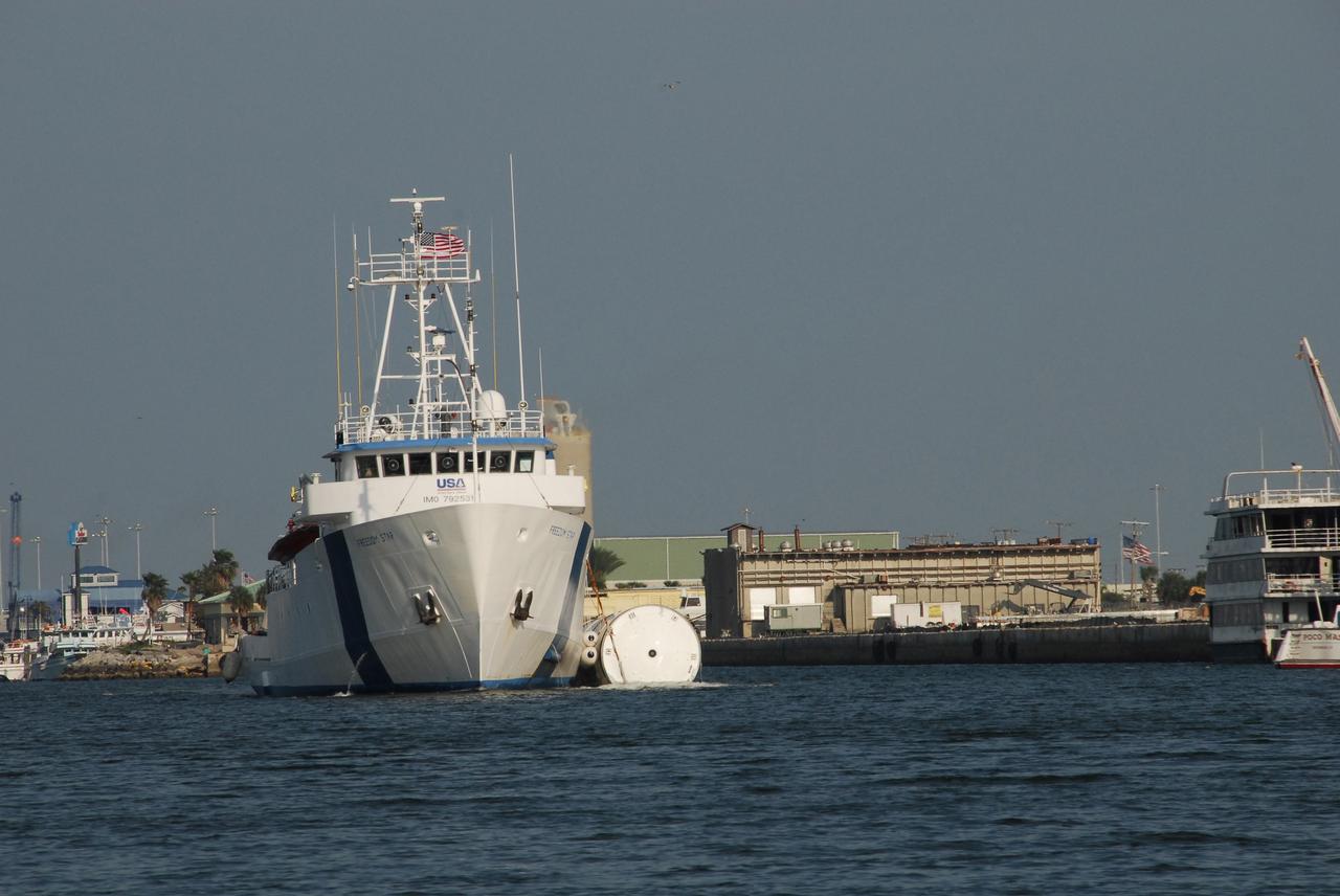 KENNEDY SPACE CENTER, FLA. --  The Freedom Star, one of NASA's solid rocket booster retrieval ships, motors through Port Canaveral with a solid rocket booster alongside.  The booster is from space shuttle Endeavour, which launched the STS-123 mission on March 11. The space shuttle’s solid rocket booster casings and associated flight hardware are recovered at sea. The boosters impact the Atlantic Ocean approximately seven minutes after liftoff. The splashdown area is a square of about 6 by 9 nautical miles located about 140 nautical miles downrange from the launch pad. The retrieval ships are stationed approximately 8 to 10 nautical miles from the impact area at the time of splashdown. As soon as the boosters enter the water, the ships accelerate to a speed of 15 knots and quickly close on the boosters, which they tow back to port.  After transfer to a position alongside the ship, the booster will be towed  to Hangar AF at Cape Canaveral Air Force Station. There, the expended boosters are disassembled, refurbished and reloaded with solid propellant for reuse.   Photo credit: NASA/Jack Pfaller