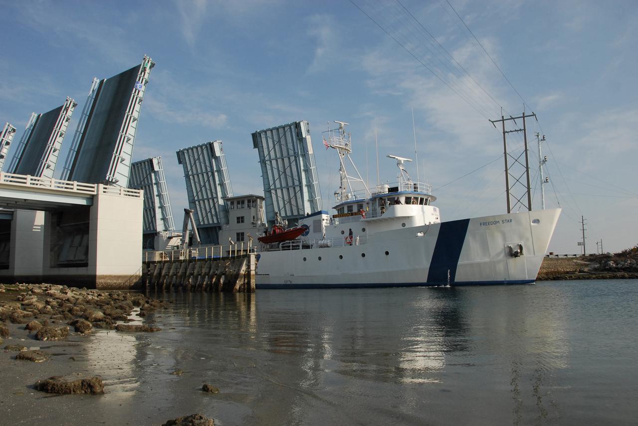 KENNEDY SPACE CENTER, FLA. --  The Freedom Star, one of NASA's solid rocket booster retrieval ships, crosses through the drawbridge over the Haulover Canal into the Banana River.  The ship is towing a solid rocket booster alongside. The booster is from space shuttle Endeavour, which launched the STS-123 mission on March 11. The space shuttle’s solid rocket booster casings and associated flight hardware are recovered at sea. The boosters impact the Atlantic Ocean approximately seven minutes after liftoff. The splashdown area is a square of about 6 by 9 nautical miles located about 140 nautical miles downrange from the launch pad. The retrieval ships are stationed approximately 8 to 10 nautical miles from the impact area at the time of splashdown. As soon as the boosters enter the water, the ships accelerate to a speed of 15 knots and quickly close on the boosters, which they tow back to port.  After transfer to a position alongside the ship, the booster will be towed  to Hangar AF at Cape Canaveral Air Force Station. There, the expended boosters are disassembled, refurbished and reloaded with solid propellant for reuse.   Photo credit: NASA/Jack Pfaller
