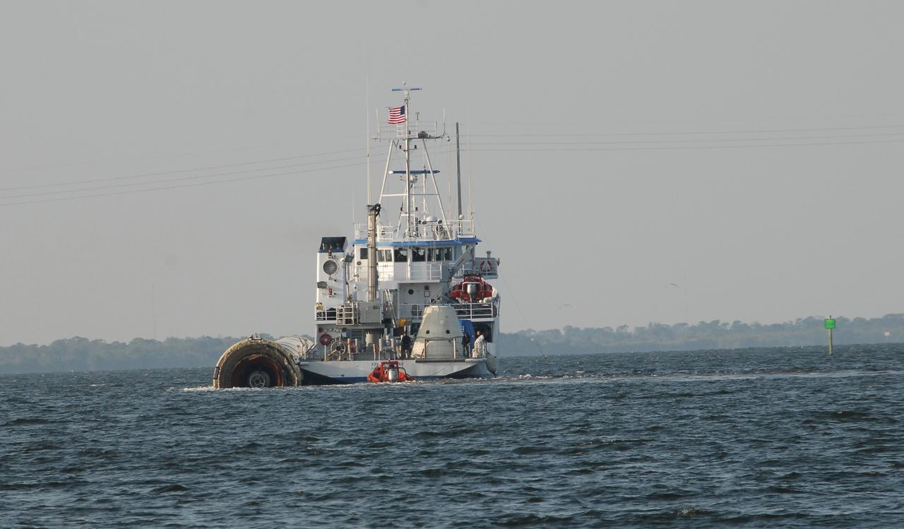 KENNEDY SPACE CENTER, FLA. --  The Freedom Star, one of NASA's solid rocket booster retrieval ships, tows a solid rocket booster alongside, heading for Hangar AF at Cape Canaveral Air Force Station. The booster is from space shuttle Endeavour, which launched the STS-123 mission on March 11. The space shuttle’s solid rocket booster casings and associated flight hardware are recovered at sea. The boosters impact the Atlantic Ocean approximately seven minutes after liftoff. The splashdown area is a square of about 6 by 9 nautical miles located about 140 nautical miles downrange from the launch pad. The retrieval ships are stationed approximately 8 to 10 nautical miles from the impact area at the time of splashdown. As soon as the boosters enter the water, the ships accelerate to a speed of 15 knots and quickly close on the boosters, which they tow back to port.  After transfer to a position alongside the ship, the booster will be towed  to Hangar AF at Cape Canaveral Air Force Station. There, the expended boosters are disassembled, refurbished and reloaded with solid propellant for reuse.   Photo credit: NASA/Jack Pfaller