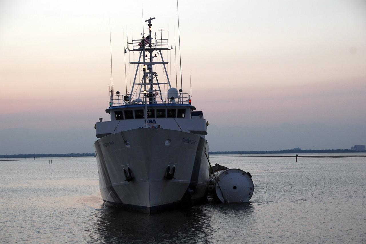KENNEDY SPACE CENTER, FLA. --   The Freedom Star, one of NASA's solid rocket booster retrieval ships, nears Hangar AF at Cape Canaveral Air Force Station with a solid rocket booster alongside. The booster is from space shuttle Endeavour, which launched the STS-123 mission on March 11. The space shuttle’s solid rocket booster casings and associated flight hardware are recovered at sea. The boosters impact the Atlantic Ocean approximately seven minutes after liftoff. The splashdown area is a square of about 6 by 9 nautical miles located about 140 nautical miles downrange from the launch pad. The retrieval ships are stationed approximately 8 to 10 nautical miles from the impact area at the time of splashdown. As soon as the boosters enter the water, the ships accelerate to a speed of 15 knots and quickly close on the boosters, which they tow back to port.  After transfer to a position alongside the ship, the booster will be towed  to Hangar AF at Cape Canaveral Air Force Station. There, the expended boosters are disassembled, refurbished and reloaded with solid propellant for reuse.   Photo credit: NASA/Jack Pfaller