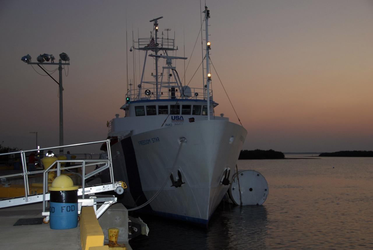 KENNEDY SPACE CENTER, FLA. --   The Freedom Star, one of NASA's solid rocket booster retrieval ships, is tied up at Hangar AF at Cape Canaveral Air Force Station with a solid rocket booster alongside. The booster is from space shuttle Endeavour, which launched the STS-123 mission on March 11. The space shuttle’s solid rocket booster casings and associated flight hardware are recovered at sea. The boosters impact the Atlantic Ocean approximately seven minutes after liftoff. The splashdown area is a square of about 6 by 9 nautical miles located about 140 nautical miles downrange from the launch pad. The retrieval ships are stationed approximately 8 to 10 nautical miles from the impact area at the time of splashdown. As soon as the boosters enter the water, the ships accelerate to a speed of 15 knots and quickly close on the boosters, which they tow back to port.  At Cape Canaveral Air Force Station, the expended boosters are disassembled, refurbished and reloaded with solid propellant for reuse.   Photo credit: NASA/Jack Pfaller