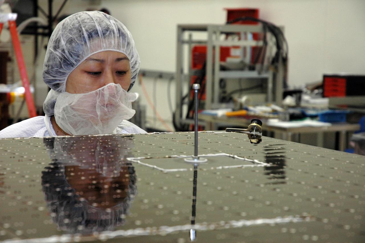 KENNEDY SPACE CENTER, FLA. - In the Astrotech payload processing facility, a General Dynamics technician studies one of twin solar arrays that will be installed on NASA's Gamma-Ray Large Area Space Telescope, or GLAST. The telescope will launch aboard a Delta II rocket May 16 from Launch Pad 17-B on Cape Canaveral Air Force Station. A powerful space observatory, the GLAST will explore the most extreme environments in the universe, and answer questions about supermassive black hole systems, pulsars and the origin of cosmic rays. It also will study the mystery of powerful explosions known as gamma-ray bursts. Photo credit: NASA/Chris Rhodes