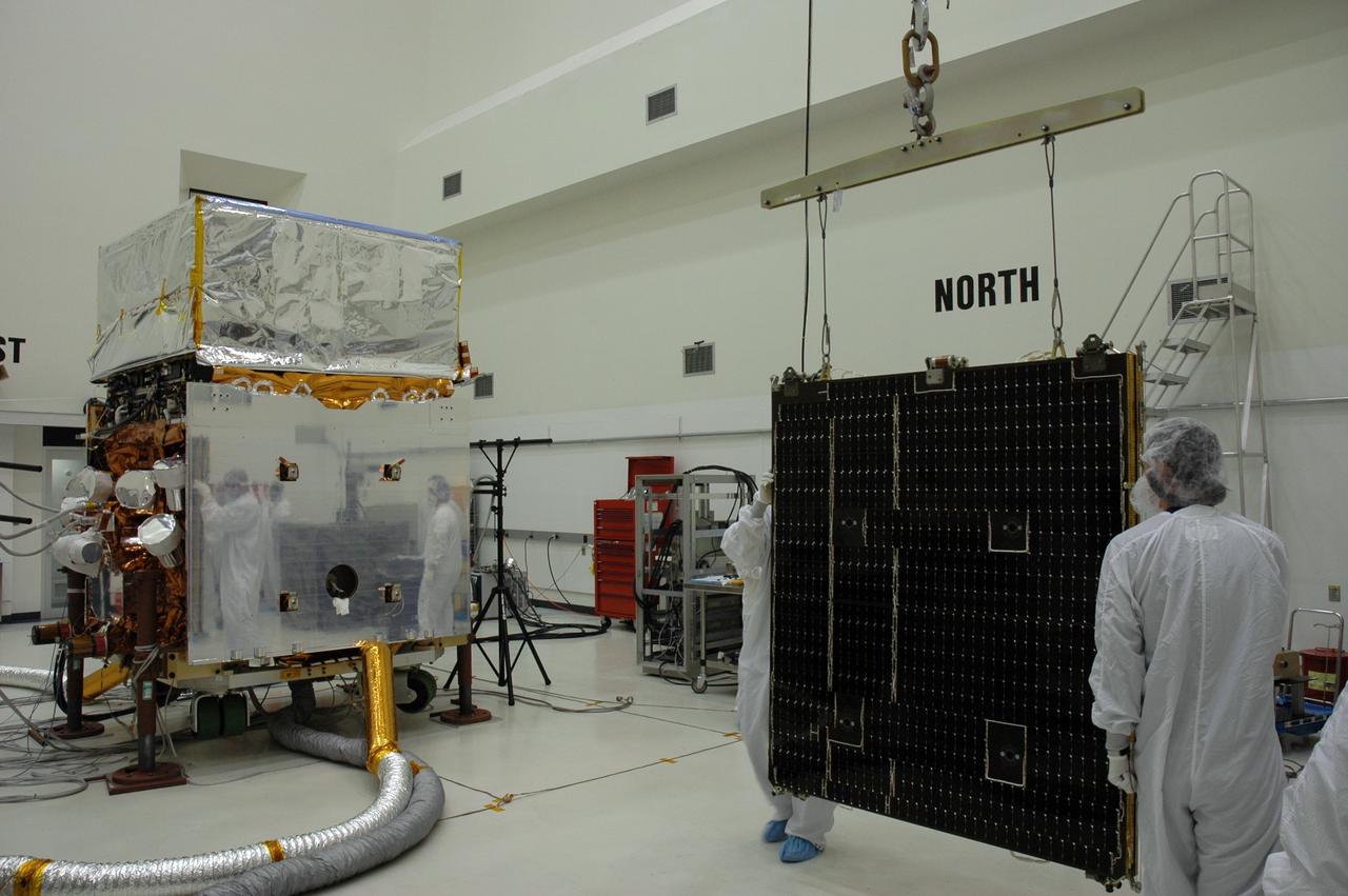 KENNEDY SPACE CENTER, FLA. - In the Astrotech payload processing facility, General Dynamics technicians guide one of twin solar arrays toward NASA's Gamma-Ray Large Area Space Telescope, or GLAST. The telescope will launch aboard a Delta II rocket May 16 from Launch Pad 17-B on Cape Canaveral Air Force Station. A powerful space observatory, the GLAST will explore the most extreme environments in the universe, and answer questions about supermassive black hole systems, pulsars and the origin of cosmic rays. It also will study the mystery of powerful explosions known as gamma-ray bursts. Photo credit: NASA/Chris Rhodes