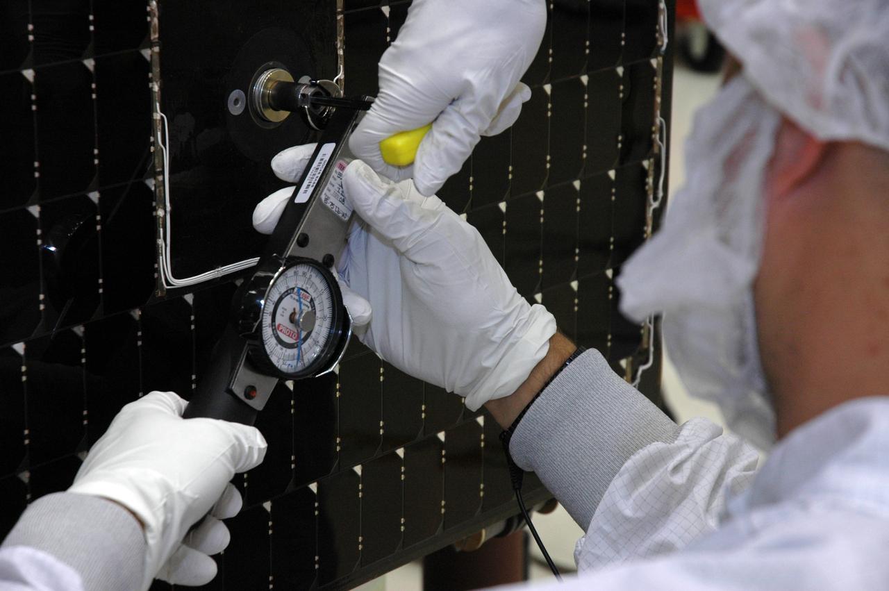 KENNEDY SPACE CENTER, FLA. - In the Astrotech payload processing facility, General Dynamics technicians use a socket wrench equipped with a torque meter to tighten the bolts holding one of twin solar arrays to NASA's Gamma-Ray Large Area Space Telescope, or GLAST. The telescope will launch aboard a Delta II rocket May 16 from Launch Pad 17-B on Cape Canaveral Air Force Station. A powerful space observatory, the GLAST will explore the most extreme environments in the universe, and answer questions about supermassive black hole systems, pulsars and the origin of cosmic rays. It also will study the mystery of powerful explosions known as gamma-ray bursts. Photo credit: NASA/Chris Rhodes