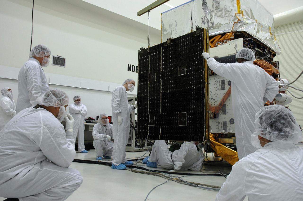 KENNEDY SPACE CENTER, FLA. - In the Astrotech payload processing facility, General Dynamics technicians install the second of twin solar arrays on NASA's Gamma-Ray Large Area Space Telescope, or GLAST. The telescope will launch aboard a Delta II rocket May 16 from Launch Pad 17-B on Cape Canaveral Air Force Station. A powerful space observatory, the GLAST will explore the most extreme environments in the universe, and answer questions about supermassive black hole systems, pulsars and the origin of cosmic rays. It also will study the mystery of powerful explosions known as gamma-ray bursts. Photo credit: NASA/Chris Rhodes