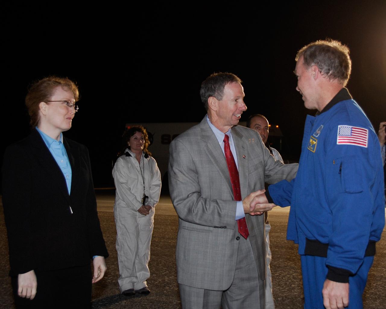 CAPE CANAVERAL, Fla. --- At NASA Kennedy Space Center's Shuttle Landing Facility, STS-123 Commander Dominic Gorie, right, is welcomed back from orbit by NASA Deputy Administrator Shana Dale, left, and NASA Administrator Mike Griffin as Media Coordinator MaryAnn Chevalier looks on.  Space shuttle Endeavour landed on Runway 15 to end the STS-123 mission, a 16-day flight to the International Space Station.  This was the 16th night landing at Kennedy.  The main landing gear touched down at 8:39:08 p.m. EDT.  The nose landing gear touched down at 8:39:17 p.m. and wheel stop was at 8:40:41 p.m.  The mission completed nearly 6.6 million miles.  The landing was on the second opportunity after the first was waved off due to unstable weather in the Kennedy Space Center area.  The STS-123 mission delivered the first segment of the Japan Aerospace Exploration Agency's Kibo laboratory and the Canadian Space Agency's two-armed robotic system, known as Dextre.  Photo credit: NASA/Kim Shiflett