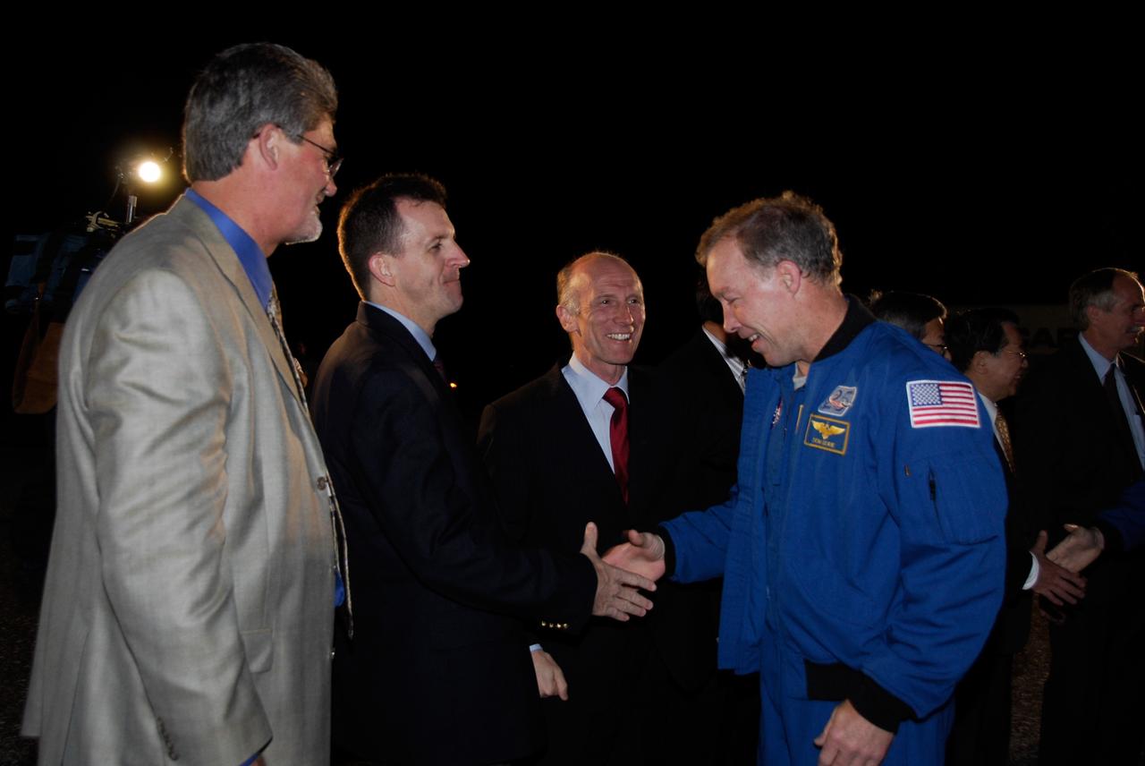 CAPE CANAVERAL, Fla. --- STS-123 Commander Dominic Gorie, right, shakes hands with LeRoy Cain, chair of the mission management team, at NASA Kennedy Space Center's Shuttle Landing Facility.  At left is Kennedy Space Center Director Bill Parsons.  Space shuttle Endeavour landed on Runway 15 to end the STS-123 mission, a 16-day flight to the International Space Station.  This was the 16th night landing at Kennedy.  The main landing gear touched down at 8:39:08 p.m. EDT.  The nose landing gear touched down at 8:39:17 p.m. and wheel stop was at 8:40:41 p.m.  The mission completed nearly 6.6 million miles.  The landing was on the second opportunity after the first was waved off due to unstable weather in the Kennedy Space Center area.  The STS-123 mission delivered the first segment of the Japan Aerospace Exploration Agency's Kibo laboratory and the Canadian Space Agency's two-armed robotic system, known as Dextre.  Photo credit: NASA/Kim Shiflett