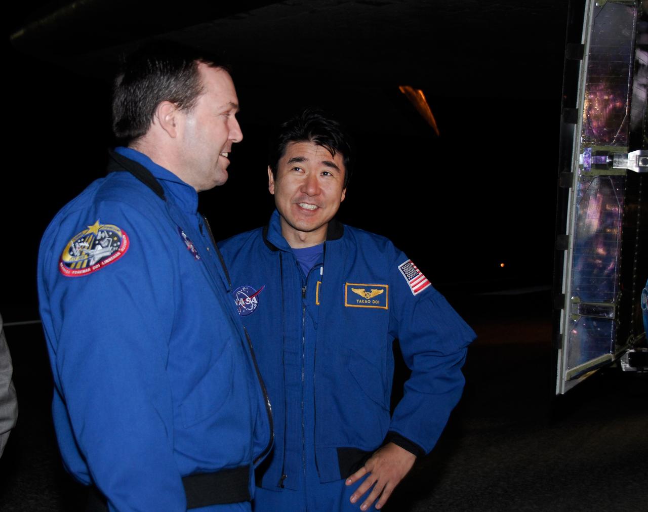 CAPE CANAVERAL, Fla. --- STS-123 Mission Specialists Mike Foreman and Takao Doi, of the Japan Aerospace Exploration Agency, have a friendly exchange under space shuttle Endeavour at NASA Kennedy Space Center's Shuttle Landing Facility.  Endeavour landed on Runway 15 to end the STS-123 mission, a 16-day flight to the International Space Station.  This was the 16th night landing at Kennedy.  The main landing gear touched down at 8:39:08 p.m. EDT.  The nose landing gear touched down at 8:39:17 p.m. and wheel stop was at 8:40:41 p.m.  The mission completed nearly 6.6 million miles.  The landing was on the second opportunity after the first was waved off due to unstable weather in the Kennedy Space Center area.   The STS-123 mission delivered the first segment of the Japan Aerospace Exploration Agency's Kibo laboratory and the Canadian Space Agency's two-armed robotic system, known as Dextre.  Photo credit: NASA/Kim Shiflett