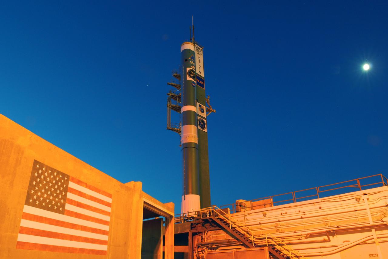 CAPE CANAVERAL, Fla. ---   Under a waning moon (upper right) at Cape Canaveral Air Force Station, the Delta II rocket to launch NASA's Gamma-ray Large Area Space Telescope, or GLAST, spacecraft is poised to receive the first of the solid rocket boosters.  A series of nine strap-on solid rocket motors will help power the first stage. The GLAST is a powerful space observatory that will explore the Universe's ultimate frontier, where nature harnesses forces and energies far beyond anything possible on Earth;  probe some of science's deepest questions, such as what our Universe is made of, and search for new laws of physics; explain how black holes accelerate jets of material to nearly light speed; and help crack the mystery of stupendously powerful explosions known as gamma-ray bursts.  Launch is currently planned for May 16 from Pad 17-B.   Photo credit: NASA/Dimitri Gerondidakis