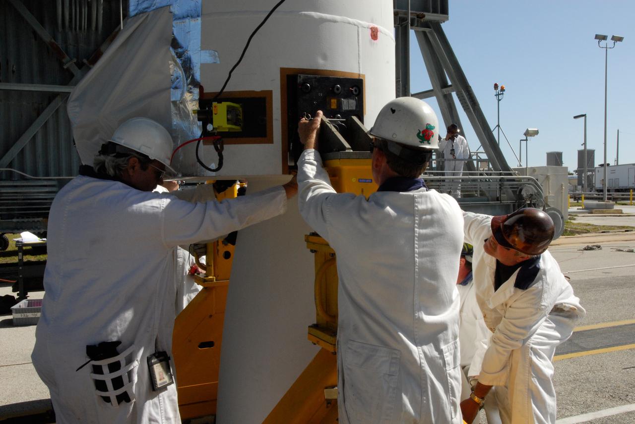 CAPE CANAVERAL, Fla. ---  At Pad 17-B on Cape Canaveral Air Force Station, technicians check the electronics on a solid rocket booster to be lifted into the mobile service tower for mating with the Delta II rocket that will launch NASA's Gamma-ray Large Area Space Telescope, or GLAST, spacecraft.  A series of nine strap-on solid rocket motors will help power the first stage. The GLAST is a powerful space observatory that will explore the Universe's ultimate frontier, where nature harnesses forces and energies far beyond anything possible on Earth;  probe some of science's deepest questions, such as what our Universe is made of, and search for new laws of physics; explain how black holes accelerate jets of material to nearly light speed; and help crack the mystery of stupendously powerful explosions known as gamma-ray bursts.  Launch is currently planned for May 16 from Pad 17-B.   Photo credit: NASA/Dimitri Gerondidakis