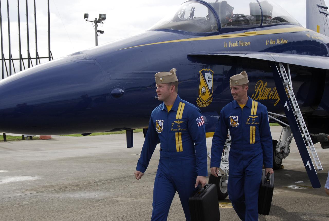 CAPE CANAVERAL, Fla. -- Blue Angel pilots Lt. Frank Weisser and Lt. Dan McShane arrive at NASA's Kennedy Space Center.  Behind them is one of the U.S. Navy F-18 Hornets flown by the Blue Angels.  The pilots flew into Kennedy to begin preparations for their involvement in the second annual Space & Air Show at Kennedy Space Center Nov. 8-9.  The air show will be only the second time the Blue Angels have performed at Kennedy.  Their precision flight team will perform high-speed passes, fast rolls, mirror formations, tight turns and their signature Delta formation showcasing the capabilities of the powerful aircraft.  The 2008 Space & Air Show will include aircraft displays and space-related exhibits on the ground and plenty of action in the skies over Kennedy.  Returning to the show is the 920th Rescue Wing, an Air Force Reserve Command combat search and rescue unit based at Patrick Air Force Base in Central Florida. Also, more than 20 astronauts and special guests will be on hand to personally meet guests, pose for photos and sign memorabilia.  Photo credit: NASA/Kim Shiflett