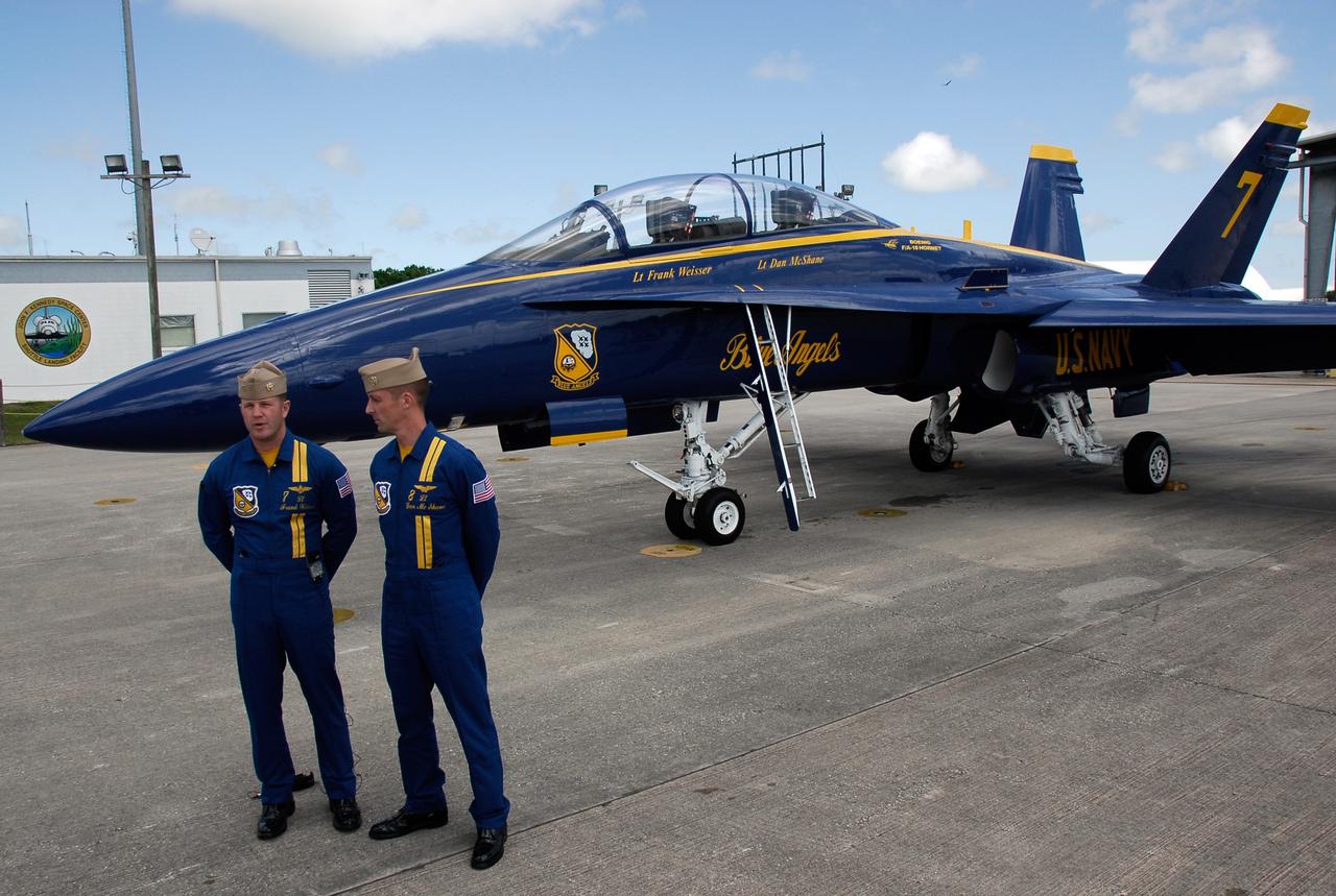 CAPE CANAVERAL, Fla. -- Blue Angel pilots Lt. Frank Weisser and Lt. Dan McShane arrive at NASA's Kennedy Space Center.  Behind them is one of the U.S. Navy F-18 Hornets flown by the Blue Angels.  The pilots flew into Kennedy to begin preparations for their involvement in the second annual Space & Air Show at Kennedy Nov. 8-9.   The air show will be only the second time the Blue Angels have performed at Kennedy.  Their precision flight team will perform high-speed passes, fast rolls, mirror formations, tight turns and their signature Delta formation showcasing the capabilities of the powerful aircraft.  The 2008 Space & Air Show will include aircraft displays and space-related exhibits on the ground and plenty of action in the skies over Kennedy.  Returning to the show is the 920th Rescue Wing, an Air Force Reserve Command combat search and rescue unit based at Patrick Air Force Base in Central Florida. Also, more than 20 astronauts and special guests will be on hand to personally meet guests, pose for photos and sign memorabilia.  Photo credit: NASA/Kim Shiflett