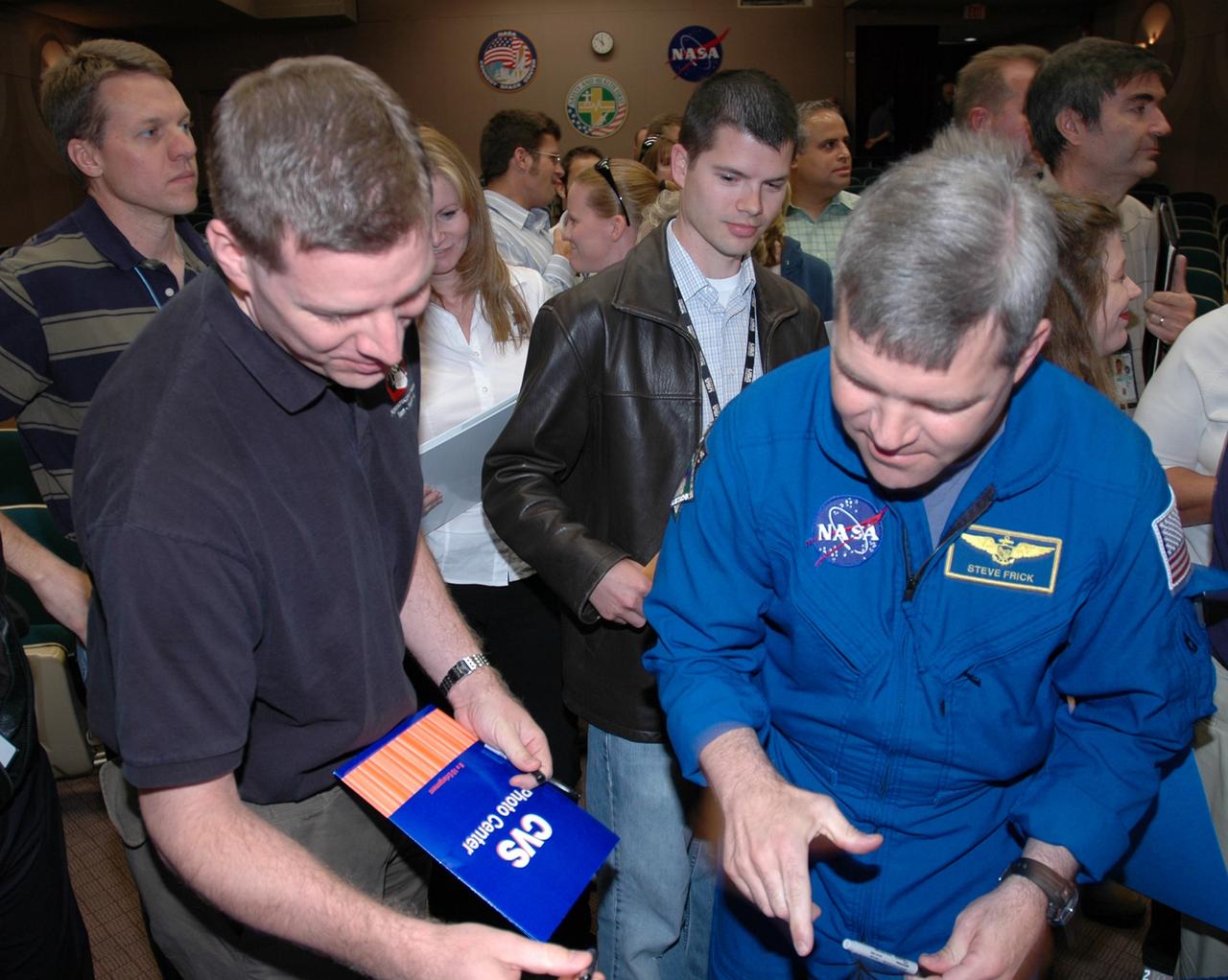 CAPE CANAVERAL, Fla. -- Following the presentation in the Training Auditorium at NASA's Kennedy Space Center, the STS-122 crew STS-122 crew signs autographs for employees. At right is Commander Steven Frick. The crew members shared personal stories, photos and videos of their challenging mission. Photo credit: NASA/Cory Huston