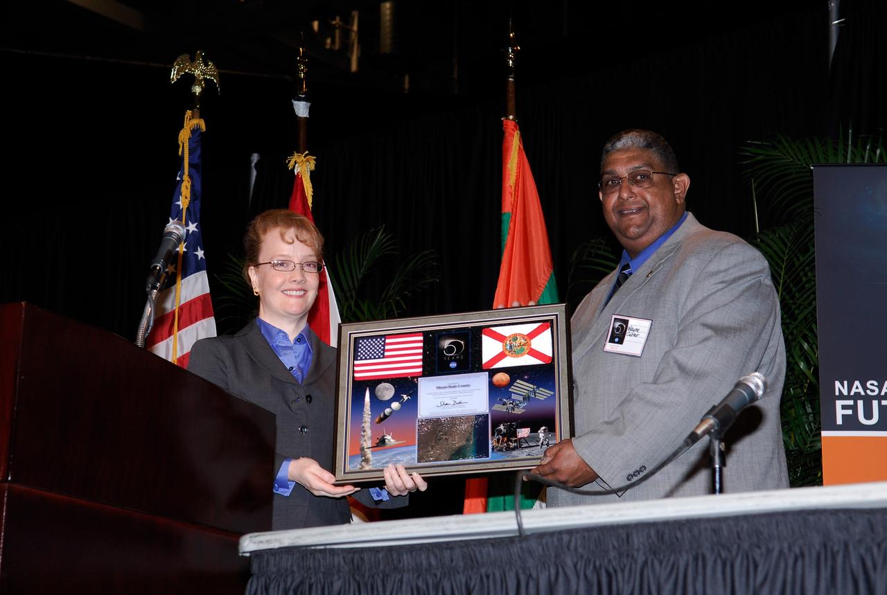 CAPE CANAVERAL, Fla. --  NASA Deputy Administrator Shana Dale (left) presents a 50th anniversary commemorative plaque to Wayne Carter during a Future Forum in Miami that focused on how space exploration benefits Florida's economy. Carter is assistant director for constituent services for the Miami-Dade County Mayor, Carlos Alveraz. The event, which included presentations and panels, was held at the University of Miami's BankUnited Center.  Among those participating were NASA Deputy Administrator Shana Dale, astronaut Carl Walz, director of the Advanced Capabilities Division in NASA's Exploration Systems Mission Directorate, and Russell Romanella, director, International Space Station and Spacecraft Processing.   Photo credit: NASA/Kim Shiflett