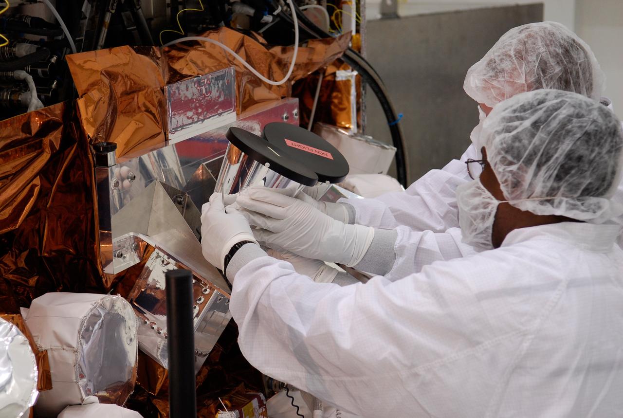 CAPE CANAVERAL, Fla. -- At the Astrotech payload processing facility in Titusville, Fla., workers install another of the star tracker sun shades on NASA's Gamma-ray Large Area Space Telescope, or GLAST, spacecraft. The GLAST is a powerful space observatory that will explore the Universe's ultimate frontier, where nature harnesses forces and energies far beyond anything possible on Earth; probe some of science's deepest questions, such as what our Universe is made of, and search for new laws of physics; explain how black holes accelerate jets of material to nearly light speed; and help crack the mystery of stupendously powerful explosions known as gamma-ray bursts. A launch date is still to be determined. Photo credit: NASA/Kim Shiflett