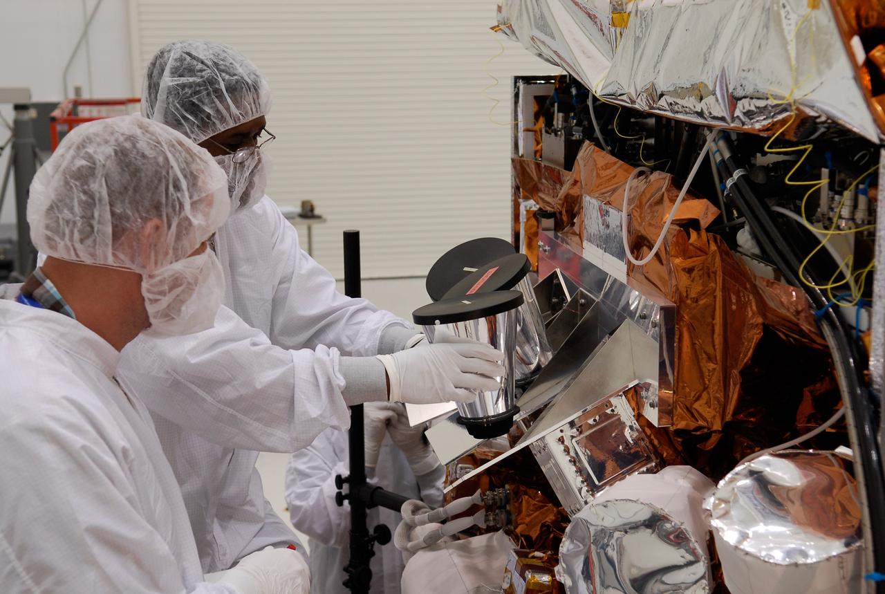 CAPE CANAVERAL, Fla. -- At the Astrotech payload processing facility in Titusville, Fla., workers install another of the star tracker sun shades on NASA's Gamma-ray Large Area Space Telescope, or GLAST, spacecraft. The GLAST is a powerful space observatory that will explore the Universe's ultimate frontier, where nature harnesses forces and energies far beyond anything possible on Earth; probe some of science's deepest questions, such as what our Universe is made of, and search for new laws of physics; explain how black holes accelerate jets of material to nearly light speed; and help crack the mystery of stupendously powerful explosions known as gamma-ray bursts. A launch date is still to be determined. Photo credit: NASA/Kim Shiflett