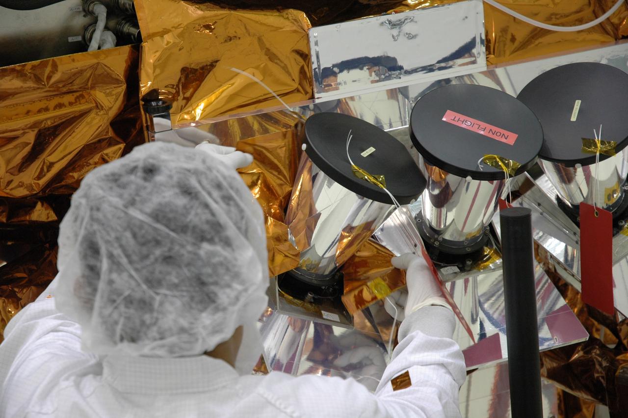 CAPE CANAVERAL, Fla. – At the Astrotech payload processing facility, technicians install insulation blankets around the star tracker sunshades on NASA's Gamma-ray Large Area Space Telescope, or GLAST, spacecraft. The GLAST is a powerful space observatory that will explore the Universe's ultimate frontier, where nature harnesses forces and energies far beyond anything possible on Earth; probe some of science's deepest questions, such as what our Universe is made of, and search for new laws of physics; explain how black holes accelerate jets of material to nearly light speed; and help crack the mystery of stupendously powerful explosions known as gamma-ray bursts. A launch date is still to be determined. Photo credit: NASA/Jim Grossmann