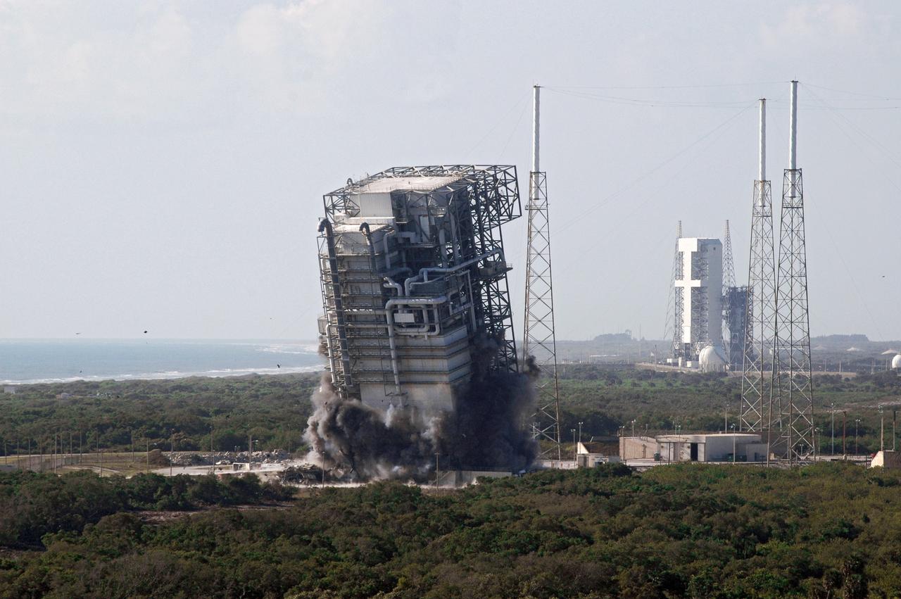 CAPE CANAVERAL, Fla. – The tilt of the mobile service tower, or gantry, at Space Launch Complex 40 on Cape Canaveral Air Force Station signals the early stages of the tower’s implosion. The tall lightning towers around it will remain. This mammoth structure, with its cavernous clean room, was used for the final spacecraft launch preparations for NASA’s Cassini spacecraft, currently orbiting Saturn. The launch occurred on Oct. 15, 1997, aboard an Air Force Titan IV-Centaur rocket. The facilities at the pad are being dismantled to make room for the construction of launch pad access and servicing facilities for the new Falcon rockets to be launched by Space Exploration Technologies, known as SpaceX. Photo credit: NASA/Cory Huston