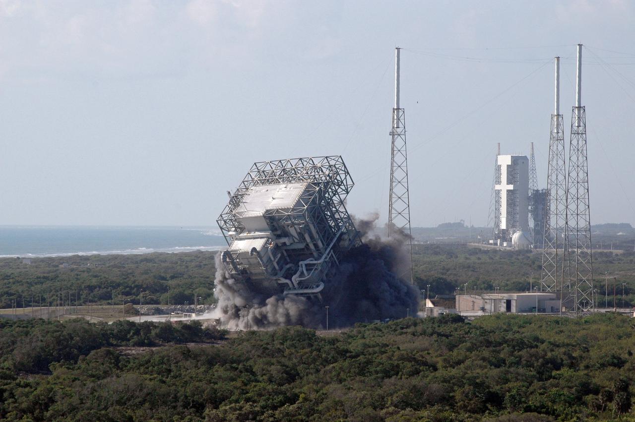 CAPE CANAVERAL, Fla. – The upper part of the mobile service tower, or gantry, at Space Launch Complex 40 on Cape Canaveral Air Force Station falls to the ground after the base was demolished. The tall lightning towers around it will remain. This mammoth structure, with its cavernous clean room, was used for the final spacecraft launch preparations for NASA’s Cassini spacecraft, currently orbiting Saturn. The launch occurred on Oct. 15, 1997, aboard an Air Force Titan IV-Centaur rocket. The facilities at the pad are being dismantled to make room for the construction of launch pad access and servicing facilities for the new Falcon rockets to be launched by Space Exploration Technologies, known as SpaceX. Photo credit: NASA/Cory Huston