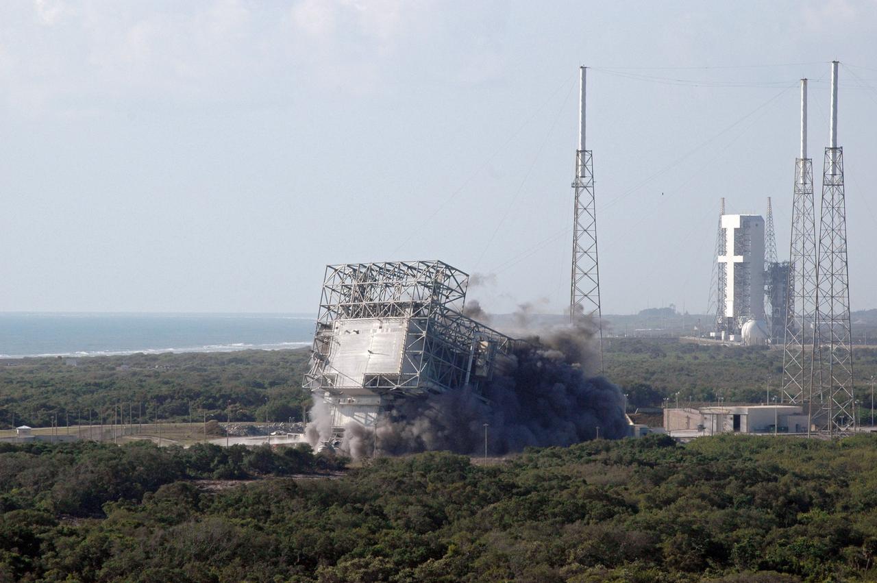 CAPE CANAVERAL, Fla. – The mobile service tower, or gantry, at Space Launch Complex 40 on Cape Canaveral Air Force Station falls to the ground after the base was demolished. The tall lightning towers around it will remain. This mammoth structure, with its cavernous clean room, was used for the final spacecraft launch preparations for NASA’s Cassini spacecraft, currently orbiting Saturn. The launch occurred on Oct. 15, 1997, aboard an Air Force Titan IV-Centaur rocket. The facilities at the pad are being dismantled to make room for the construction of launch pad access and servicing facilities for the new Falcon rockets to be launched by Space Exploration Technologies, known as SpaceX. Photo credit: NASA/Cory Huston