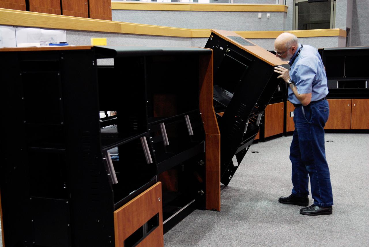 CAPE CANAVERAL, Fla. -- In Firing Room No. 1 in the Launch Control Center at NASA's Kennedy Space Center, a worker holds on to a cabinet being put together to hold equipment that will support the future Ares rocket launches as part of the Constellation Program. Future astronauts will ride to orbit on Ares I, which uses a single five-segment solid rocket booster, a derivative of the space shuttle's solid rocket booster, for the first stage. Ares will be launched from Pad 39B, which is being reconfigured from supporting space shuttle launches. The Launch Control Center firing rooms face the launch pads. Photo credit: NASA/Kim Shiflett