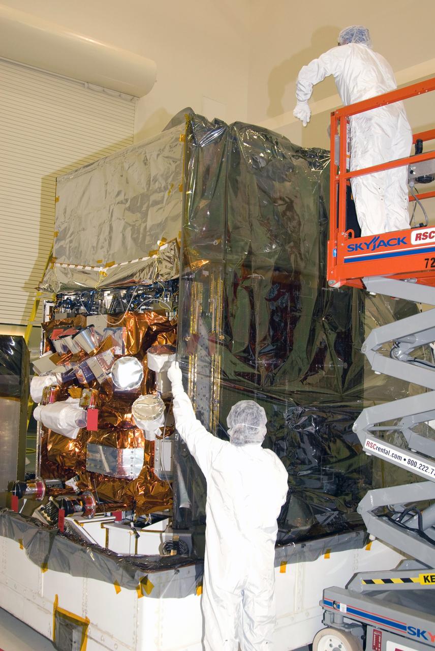 CAPE CANAVERAL, Fla. --  At the Astrotech payload processing facility in Titusville, Fla., technicians stretch protective cover over NASA's Gamma-ray Large Area Space Telescope, or GLAST, spacecraft.  GLAST is being prepared for its move to the Hazardous Processing Facility for fueling.  The GLAST is a powerful space observatory that will explore the universe's ultimate frontier, where nature harnesses forces and energies far beyond anything possible on Earth;  probe some of science's deepest questions, such as what our Universe is made of, and search for new laws of physics; explain how black holes accelerate jets of material to nearly light speed; and help crack the mystery of stupendously powerful explosions known as gamma-ray bursts. A launch date is still to be determined.  Photo credit: NASA/Mike Kerley