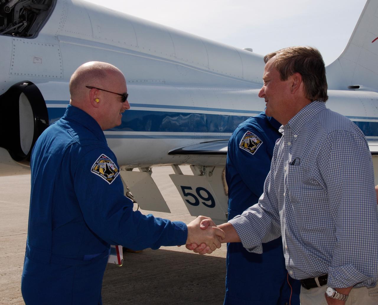 CAPE CANAVERAL, Fla. --   The crew of space shuttle Discovery's STS-124 mission arrive at NASA Kennedy Space Center's Shuttle Landing Facility to take part in the Terminal Countdown Demonstration Test, or TCDT. Here, Commander Mark Kelly is greeted by Shuttle Launch Director Mike Leinbach. Behind Leinbach is Mission Specialist Greg Chamitoff.  TCDT is a rehearsal for launch that includes practicing emergency procedures, handling on-orbit equipment, and simulating a launch countdown. On the STS-124 mission, the crew will deliver and install the Japanese Experiment Module – Pressurized Module and Japanese Remote Manipulator System.  Discovery's launch is targeted for May 31.  Photo credit: NASA/Kim Shiflett