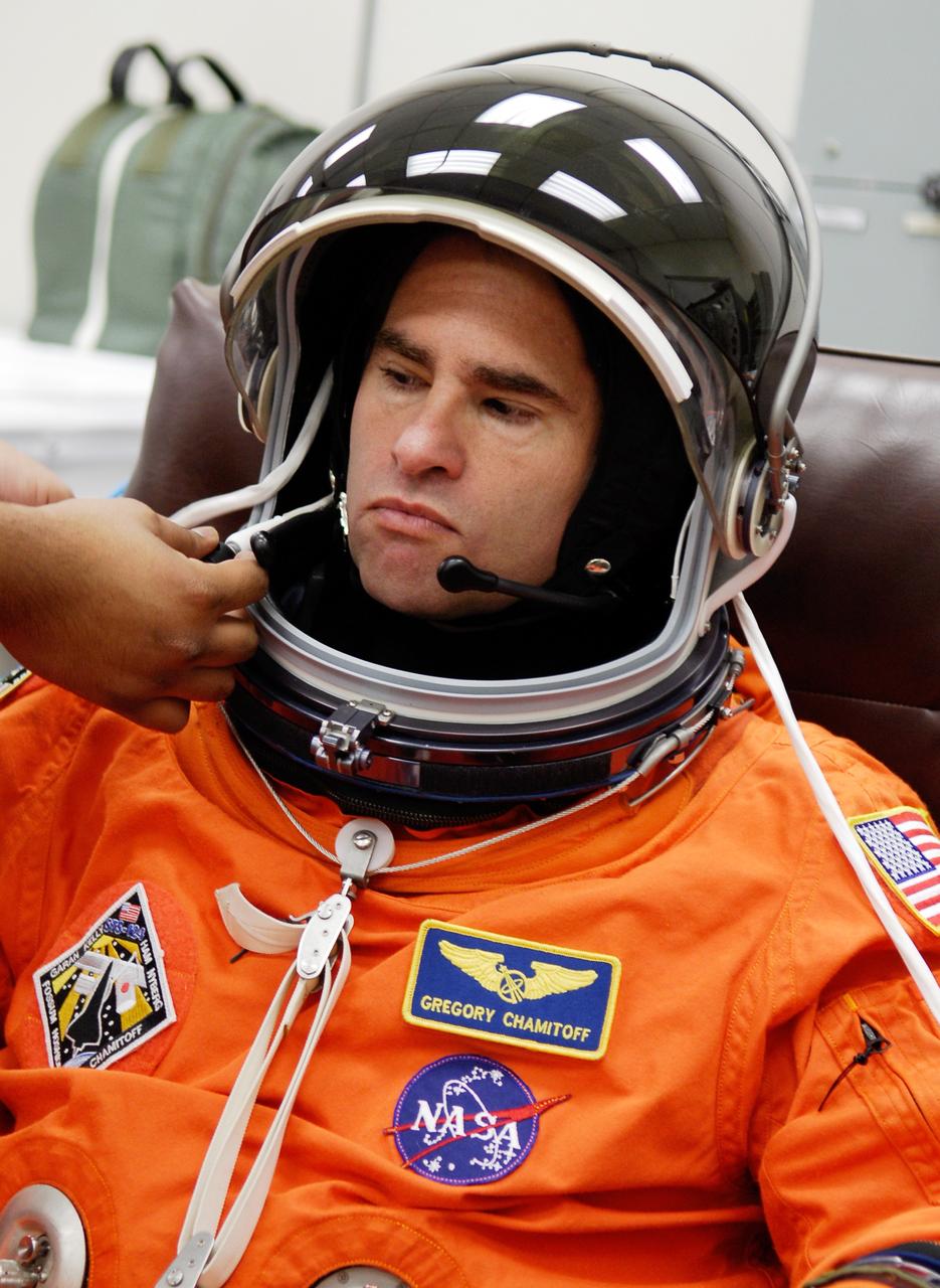 CAPE CANAVERAL, Fla. -- In the Operations and Checkout Building at NASA's Kennedy Space Center, a technician helps STS-124 Mission Specialist Greg Chamitoff with the communication piece of his helmet. Chamitoff has donned his launch-and-entry suit for the simulated launch countdown. The simulation is the culmination of the launch dress rehearsal called the terminal countdown demonstration test. TCDT provides astronauts and ground crews with an opportunity to participate in various simulated countdown activities, including equipment familiarization and emergency training. On the STS-124 mission, the crew will deliver and install the Japanese Experiment Module – Pressurized Module and Japanese Remote Manipulator System. Discovery's launch is targeted for May 31. Photo credit: NASA/Kim Shiflett