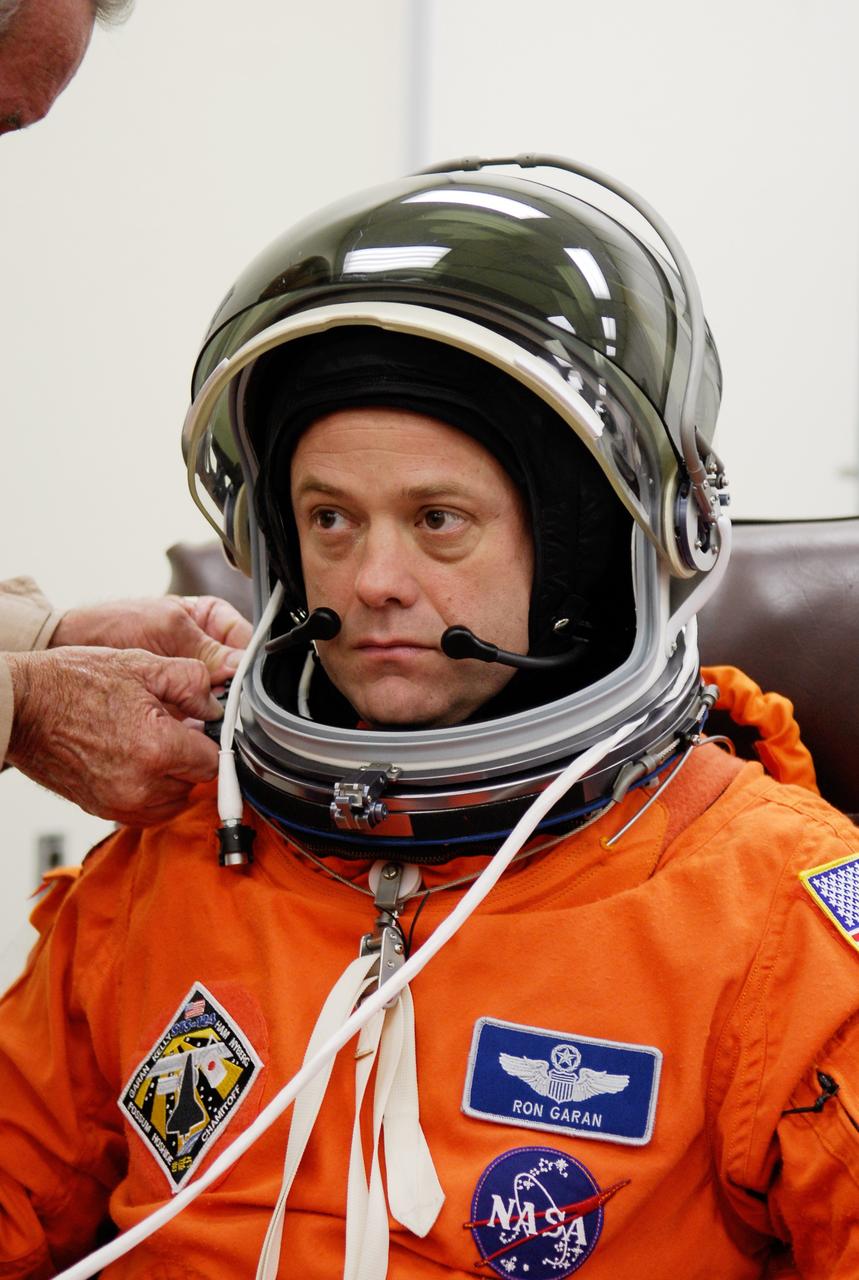 CAPE CANAVERAL, Fla. -- In the Operations and Checkout Building at NASA's Kennedy Space Center, a technician helps STS-124 Mission Specialist Ron Garan with the communication piece of his helmet. Garan has donned his launch-and-entry suit for the simulated launch countdown. The simulation is the culmination of the launch dress rehearsal called the terminal countdown demonstration test. TCDT provides astronauts and ground crews with an opportunity to participate in various simulated countdown activities, including equipment familiarization and emergency training. On the STS-124 mission, the crew will deliver and install the Japanese Experiment Module – Pressurized Module and Japanese Remote Manipulator System. Discovery's launch is targeted for May 31. Photo credit: NASA/Kim Shiflett